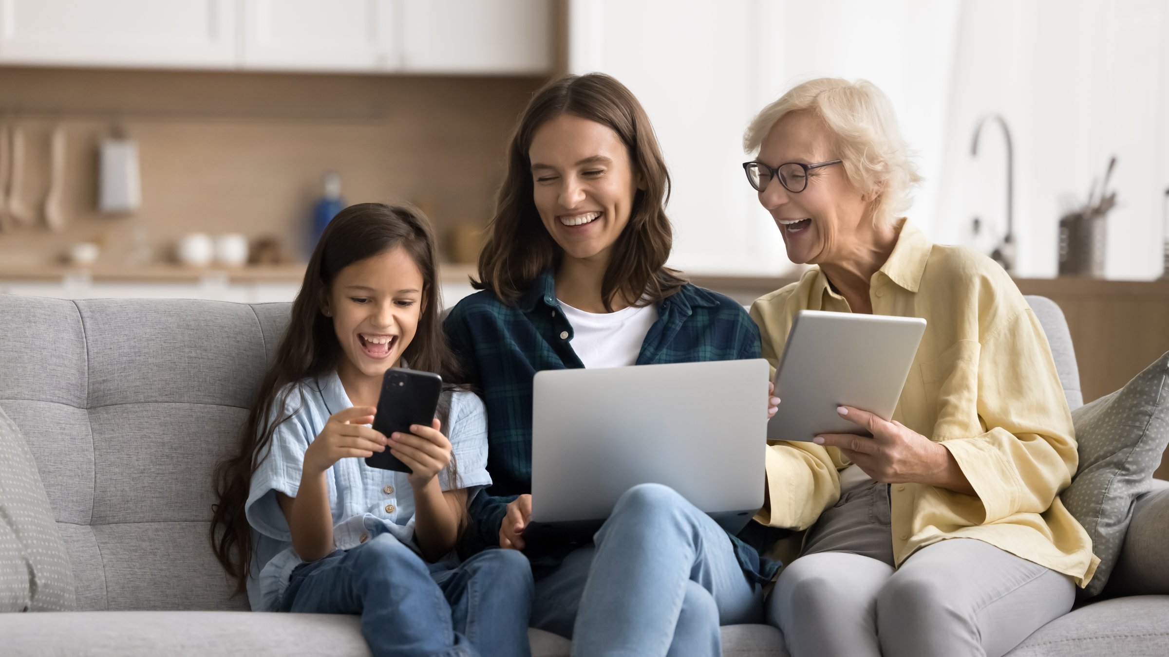 Happy kid, young mother and blonde mature grandmother using gadgets