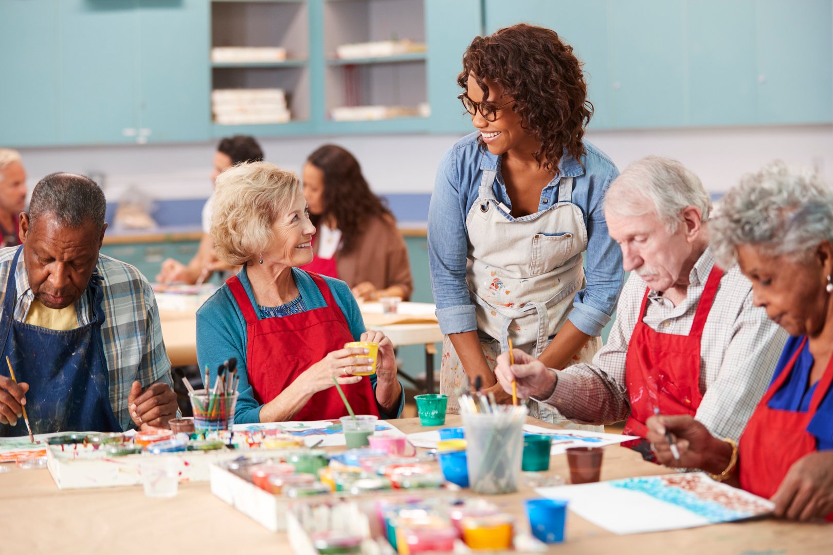 Group Of Retired Seniors Attending Art Class In Community Centre With Teacher