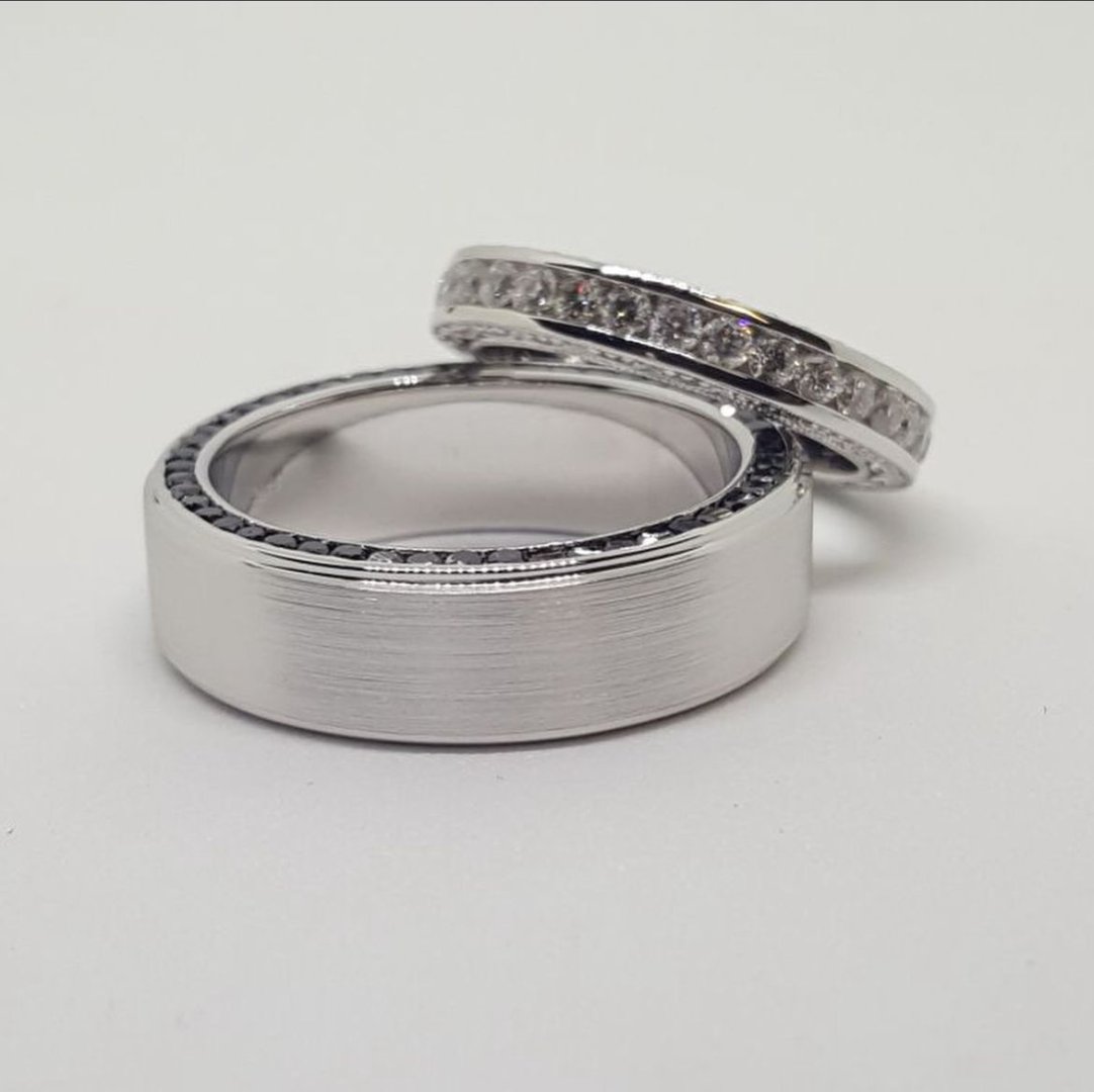 Two silver rings: one plain with a smooth finish, the other encrusted with small diamonds.