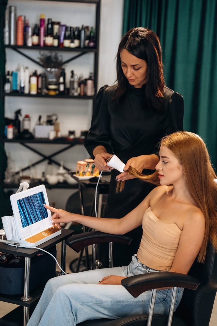 Macro view, examining the hair. Woman is in a beauty salon with hair stylist.