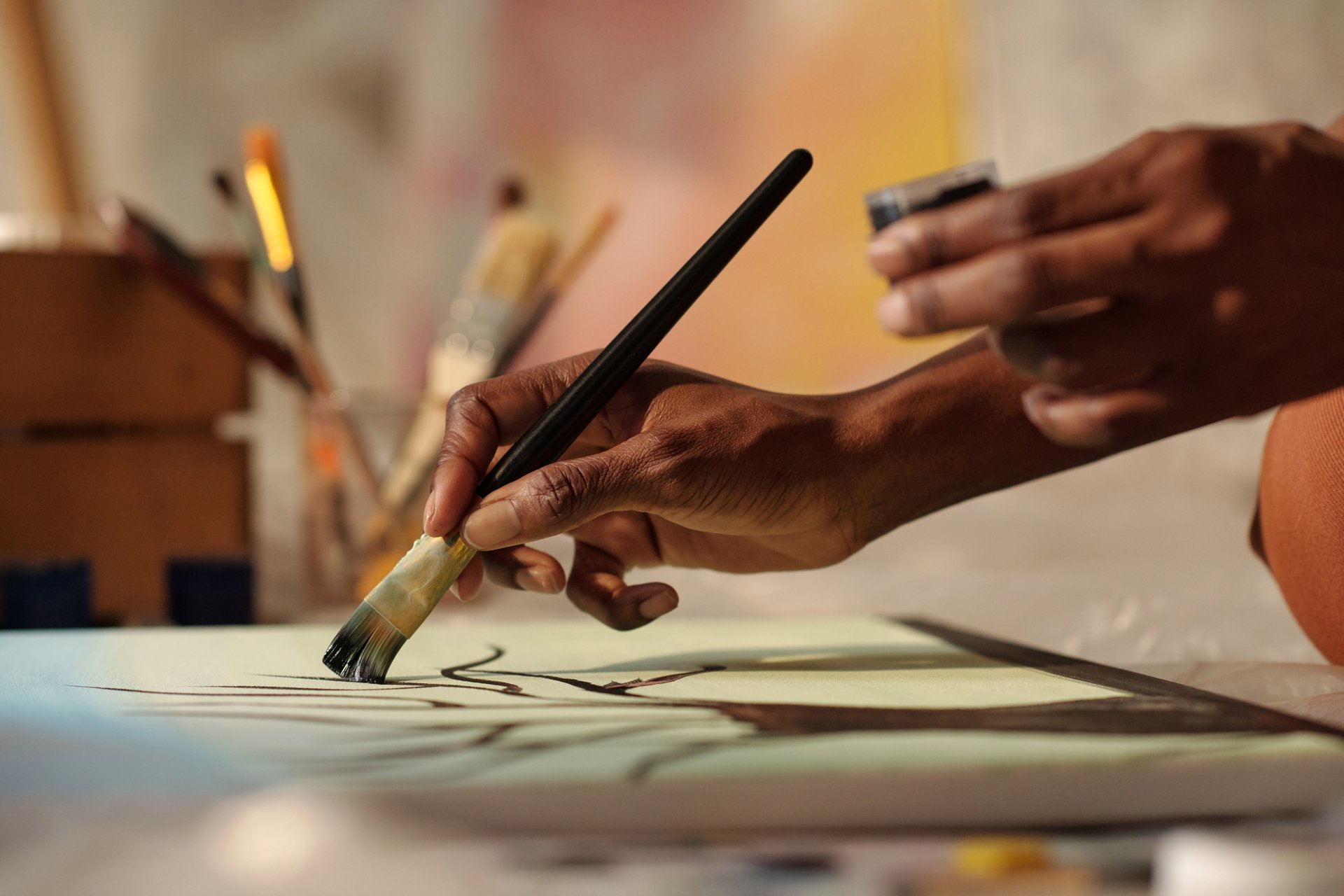 Vista cercana de mano de artista sosteniendo pincel mientras pinta