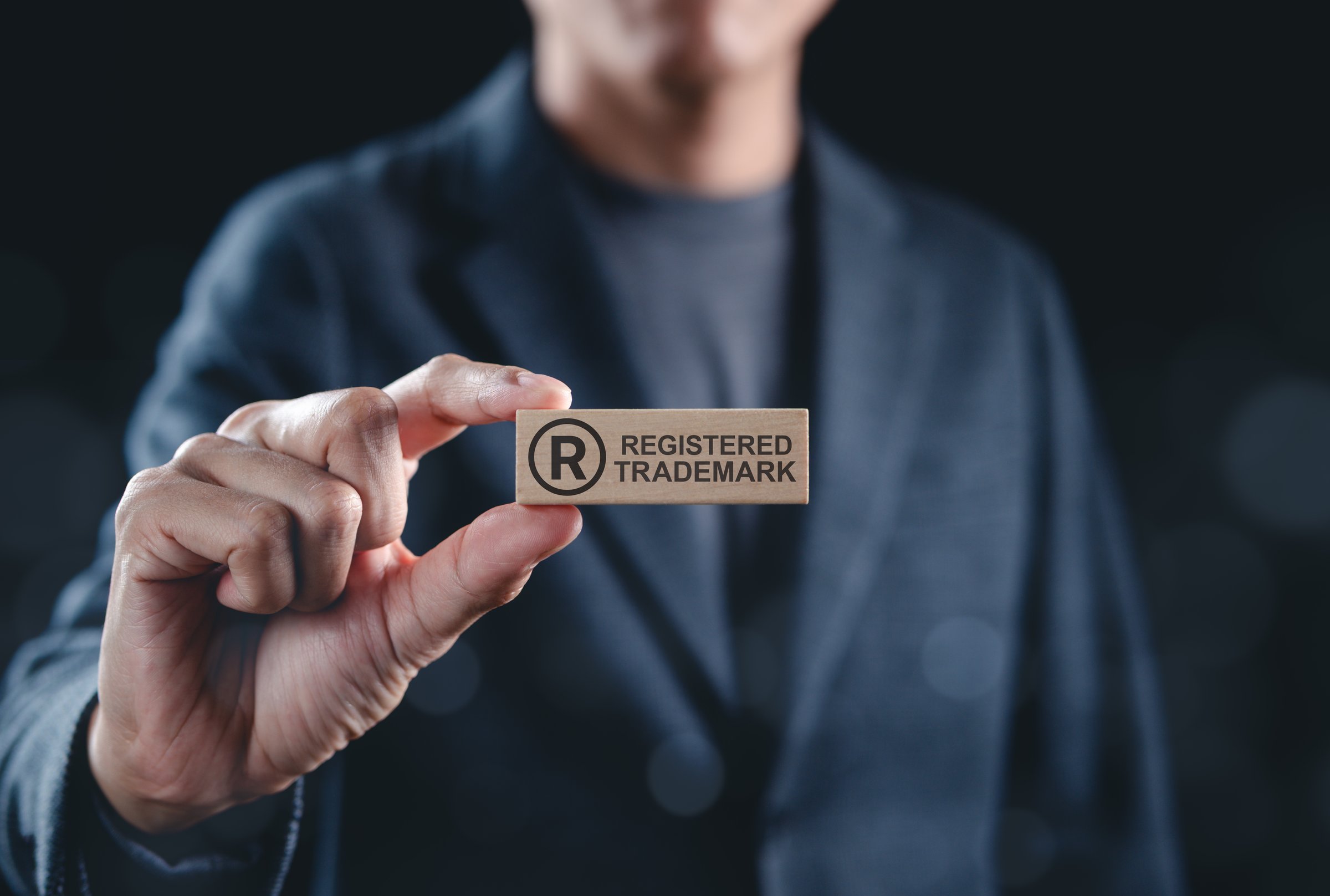 Registered Trademark Symbol and Intellectual Property Concept. Man holds wooden block registered trademark symbol and text representing intellectual property, copyright, patent, and brand protection.