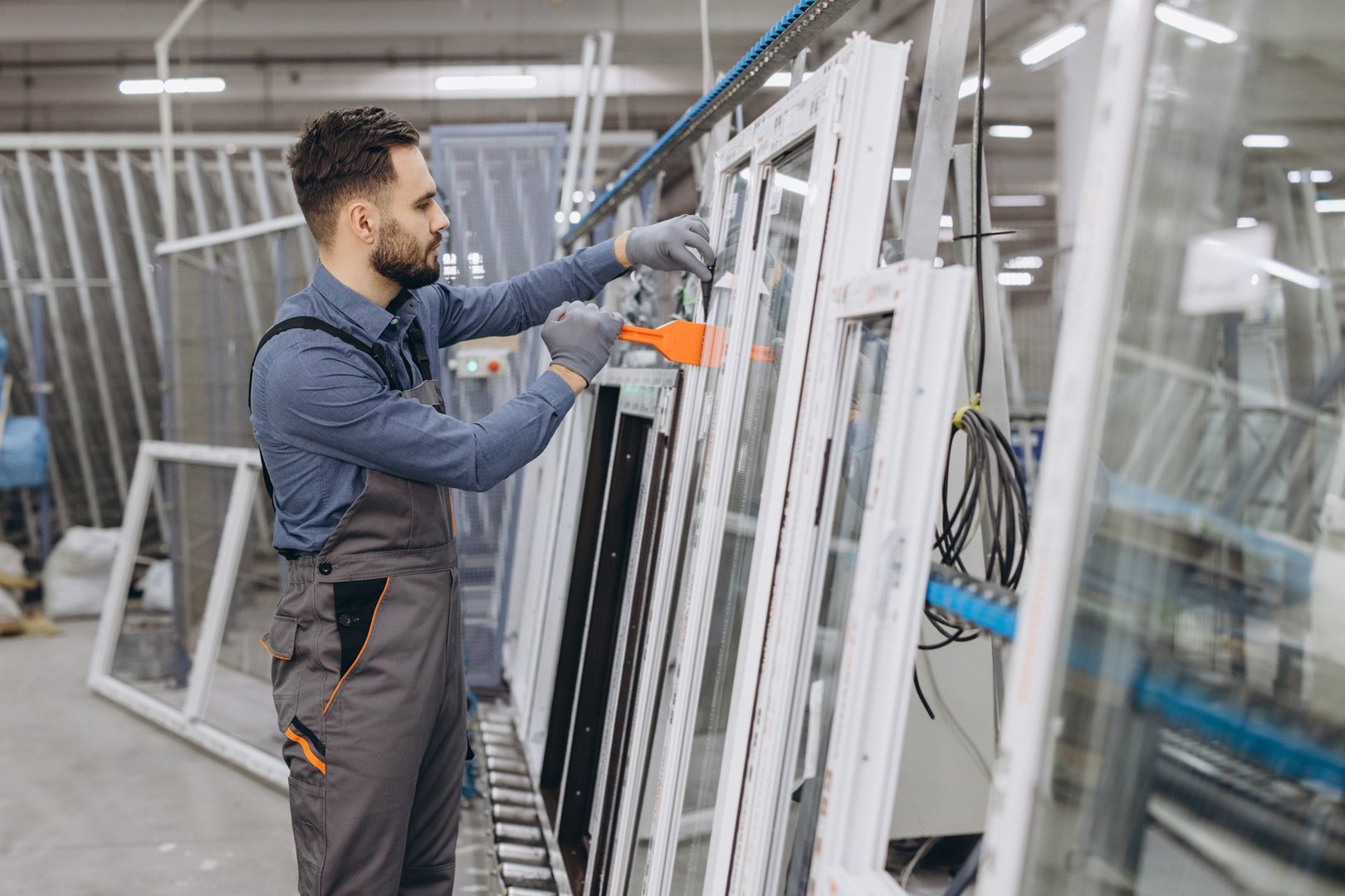 Factory worker assembling aluminum and pvc windows and doors in a large industrial production space