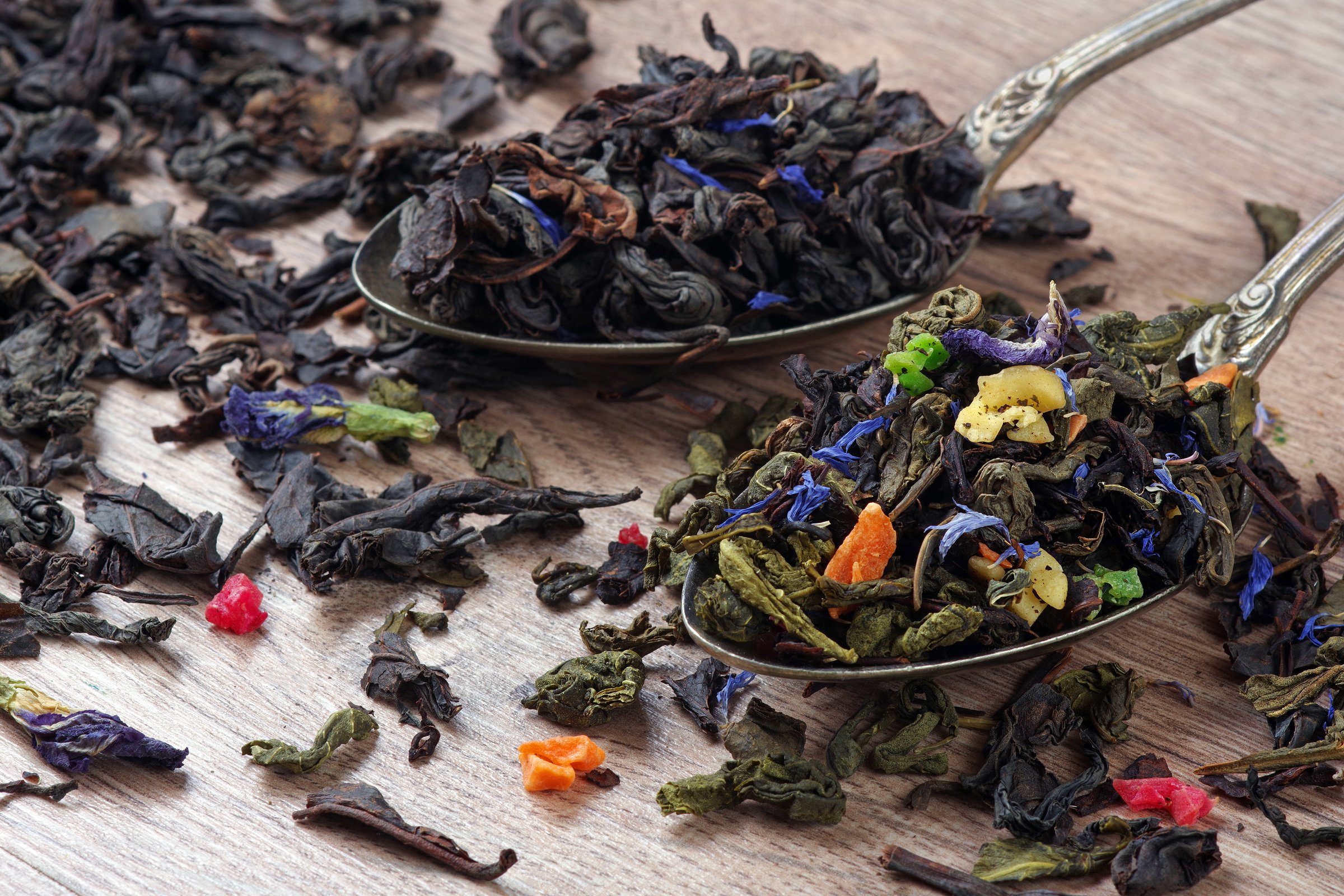 different types of tea in spoons. blended green tea and black tea on the table.