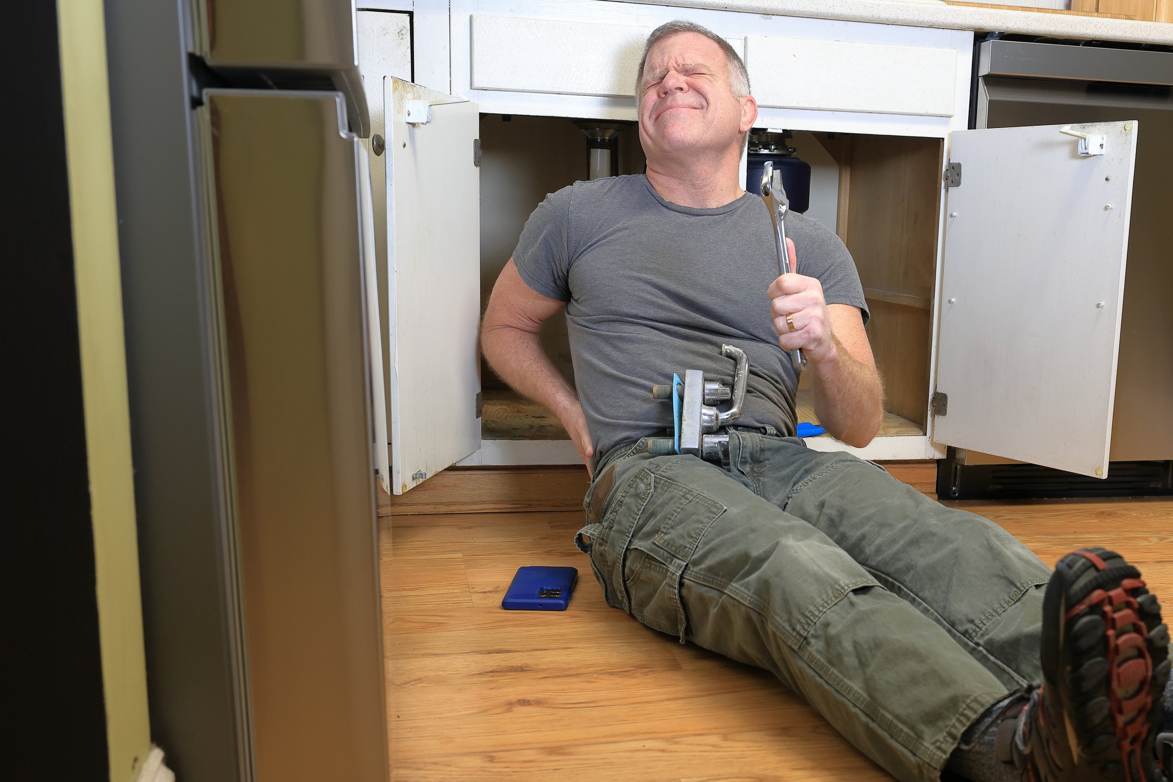 Middle aged homeowner replaces the faucet in his kitchen sink