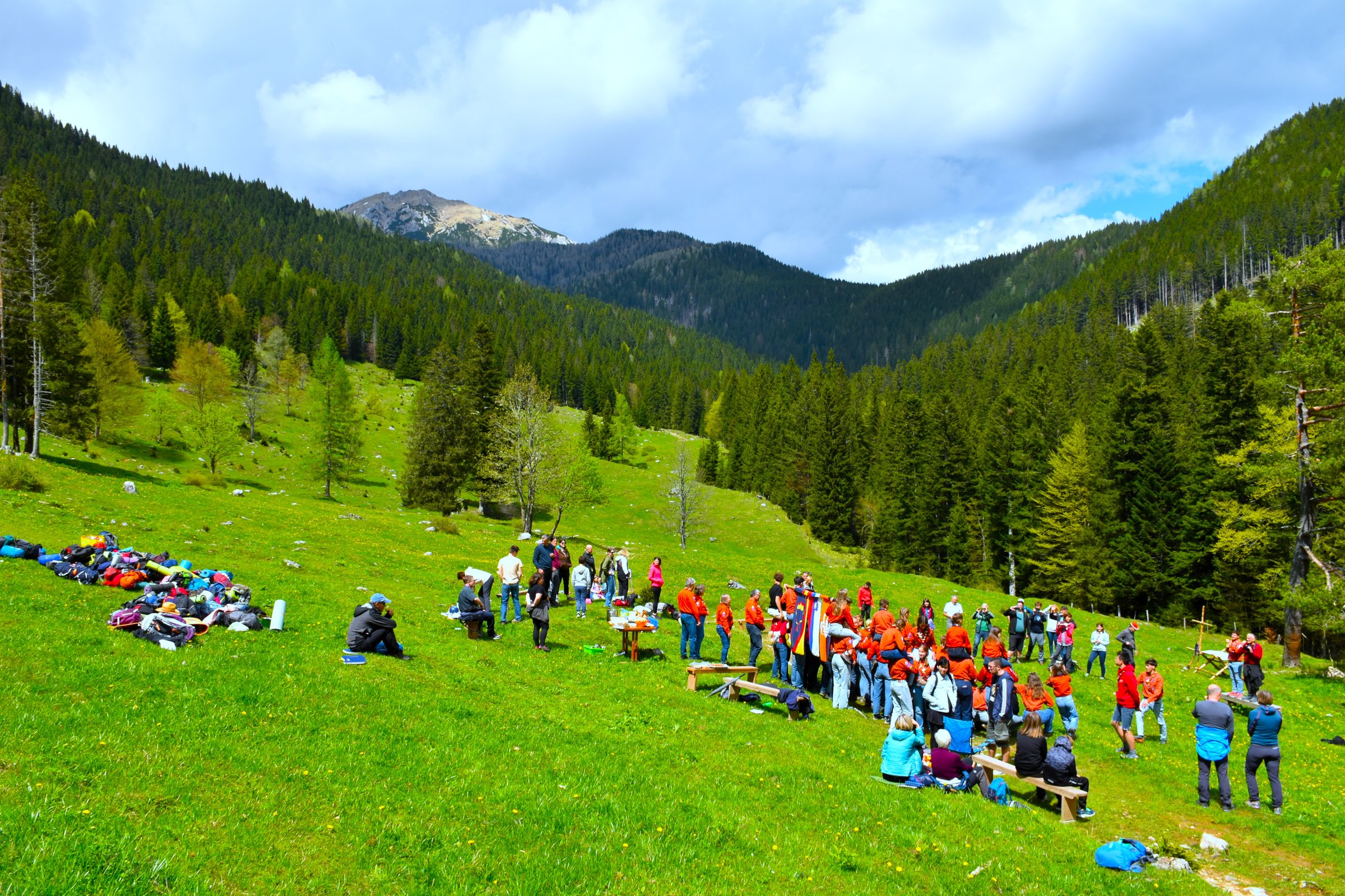 Gathering of the Slovenian catholic girl guides and boy scouts association at a meadow at Uskovnica alpine paster with a coniferous forest at the edge in Julian alps, Gorenjska, Slovenia