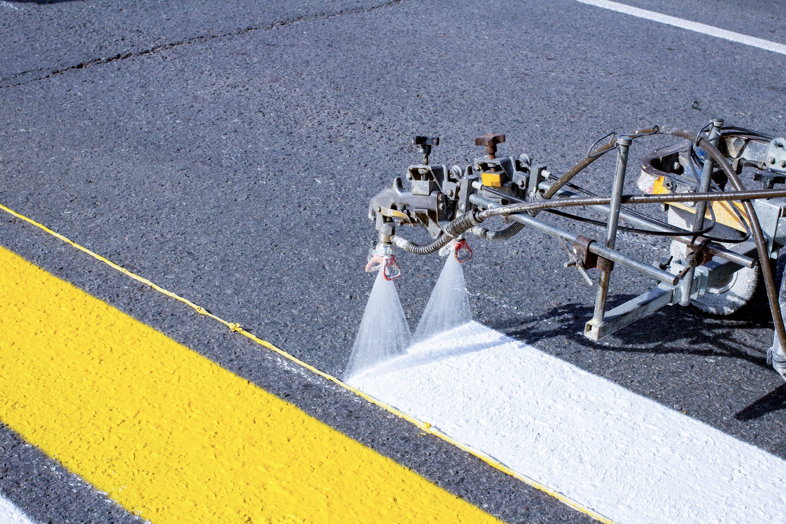 A team of workers drawing a pedestrian crossing in early spring using automated equipment on fresh asphalt