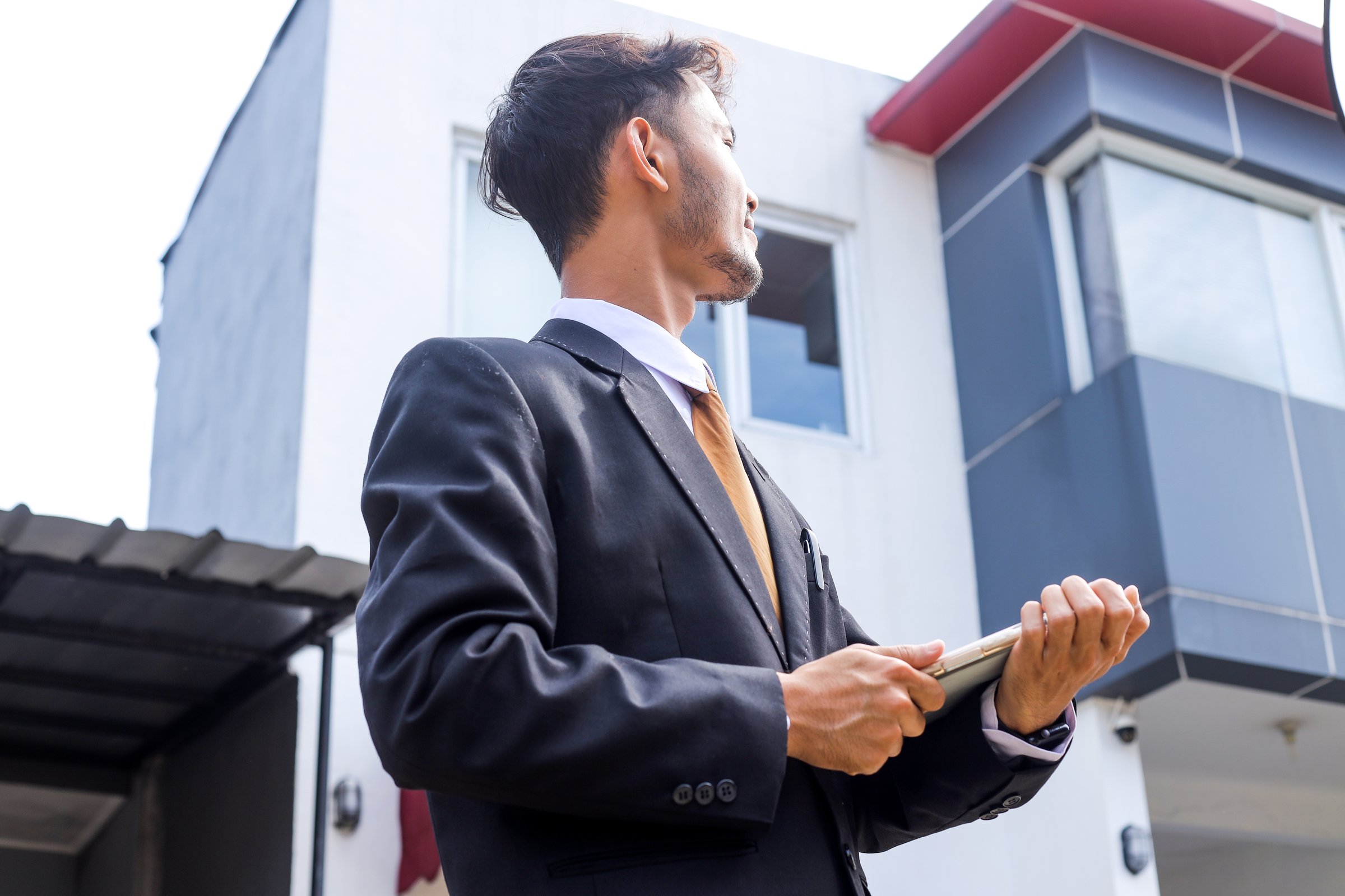 Confident real estate agent With Tablet Inspecting Stunning Modern House Exterior