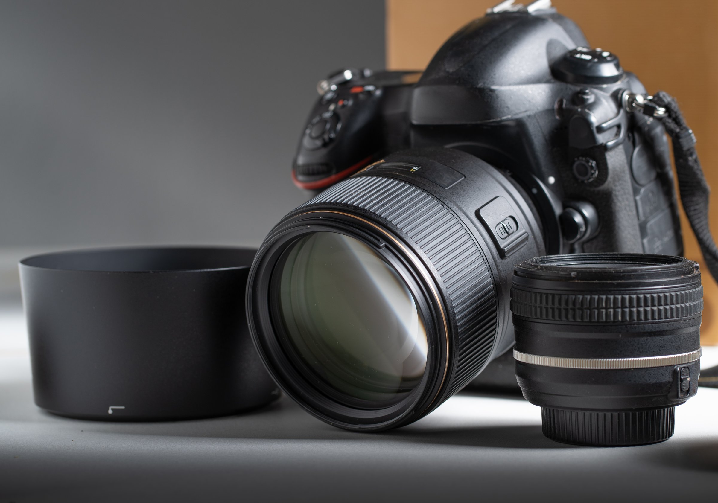 Camera and lenses. Details of a modern single reflex lens camera surrounded by several photographic lenses.