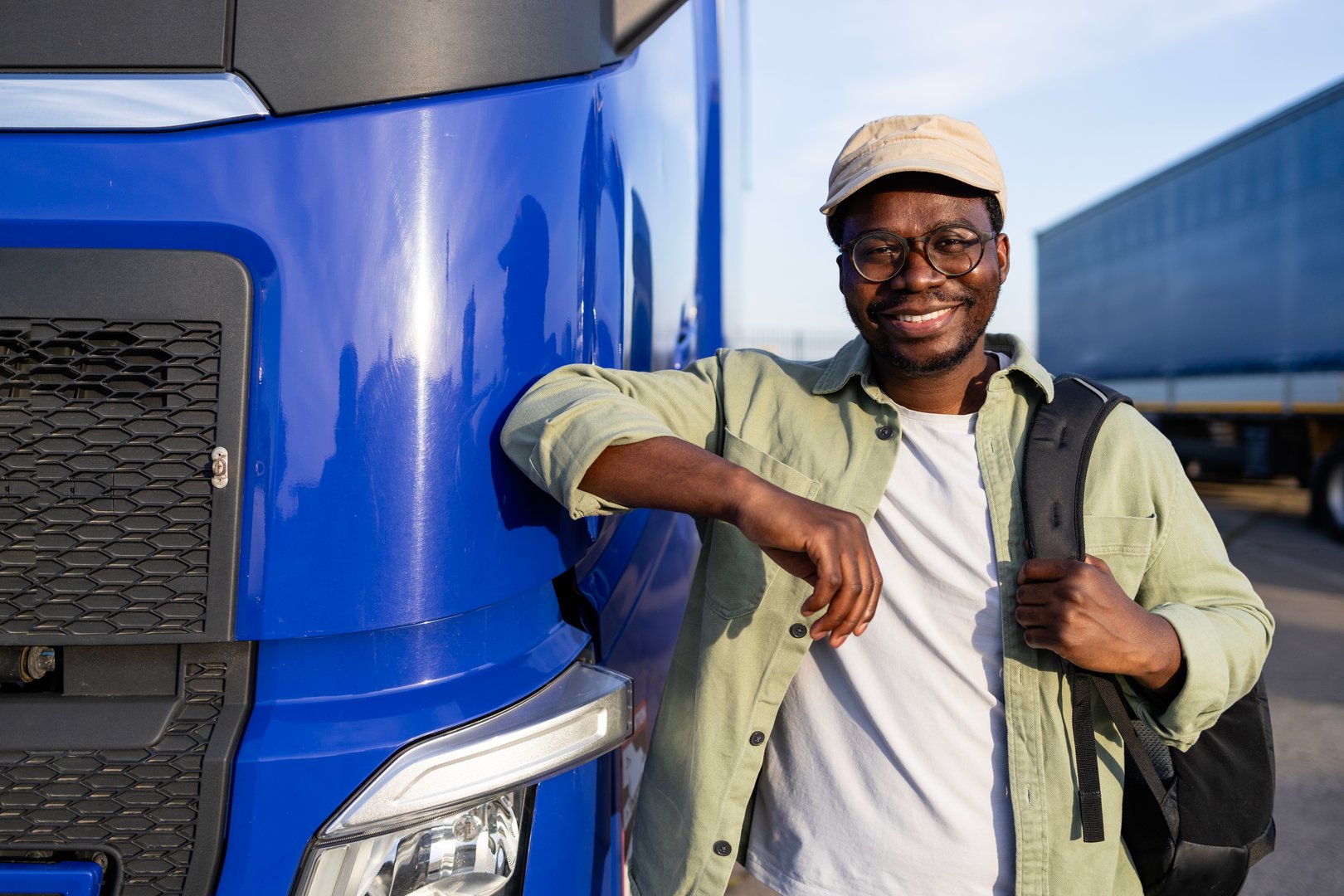 Positive and smiling driver standing by his truck ready to drive.