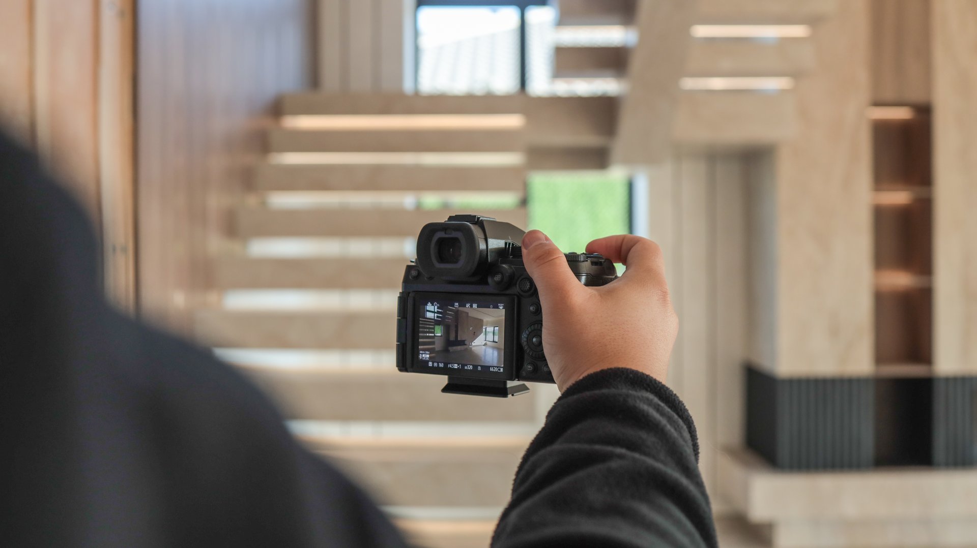 A person is holding a camera, capturing a beautiful architectural design with a staircase