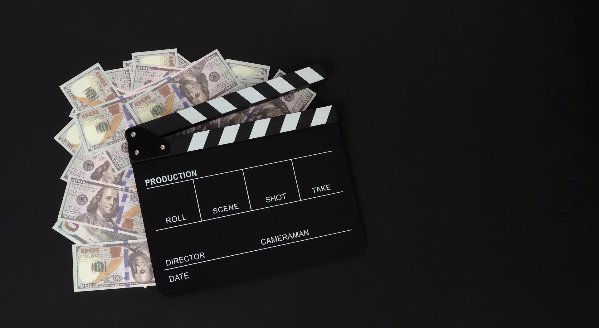 Clapper board and us dollar banknotes on balck background
