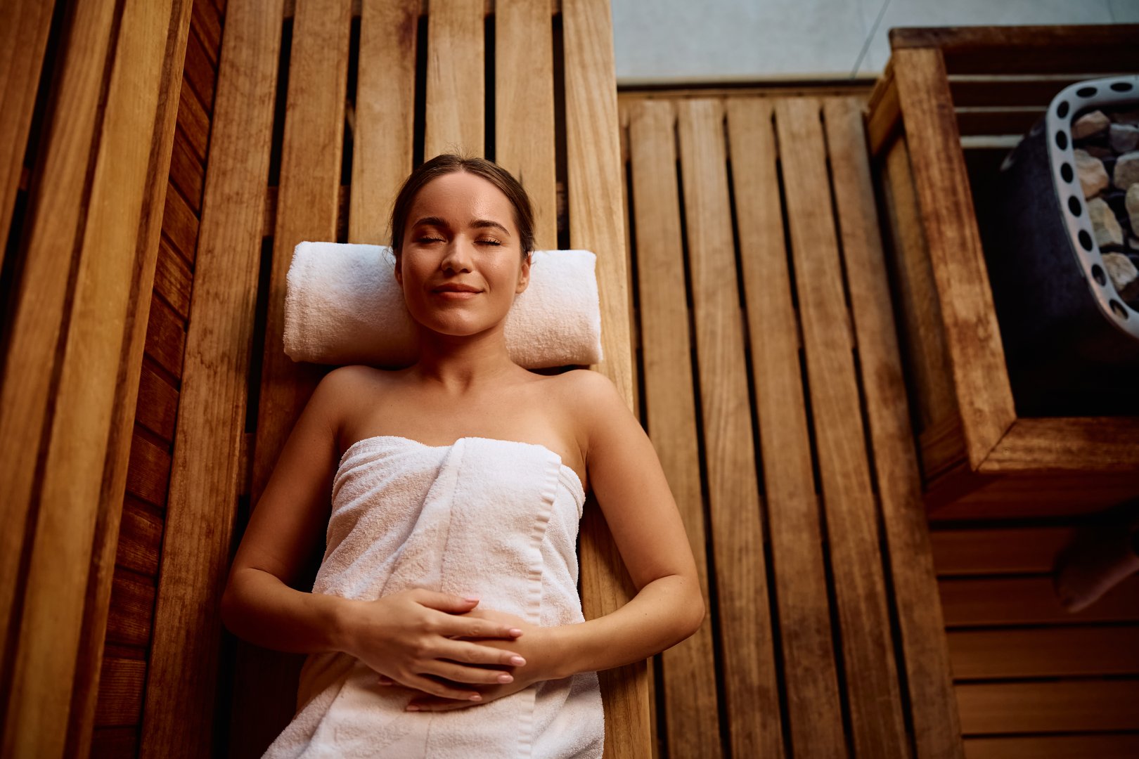 High angle view of woman relaxing with eye closed in sauna.