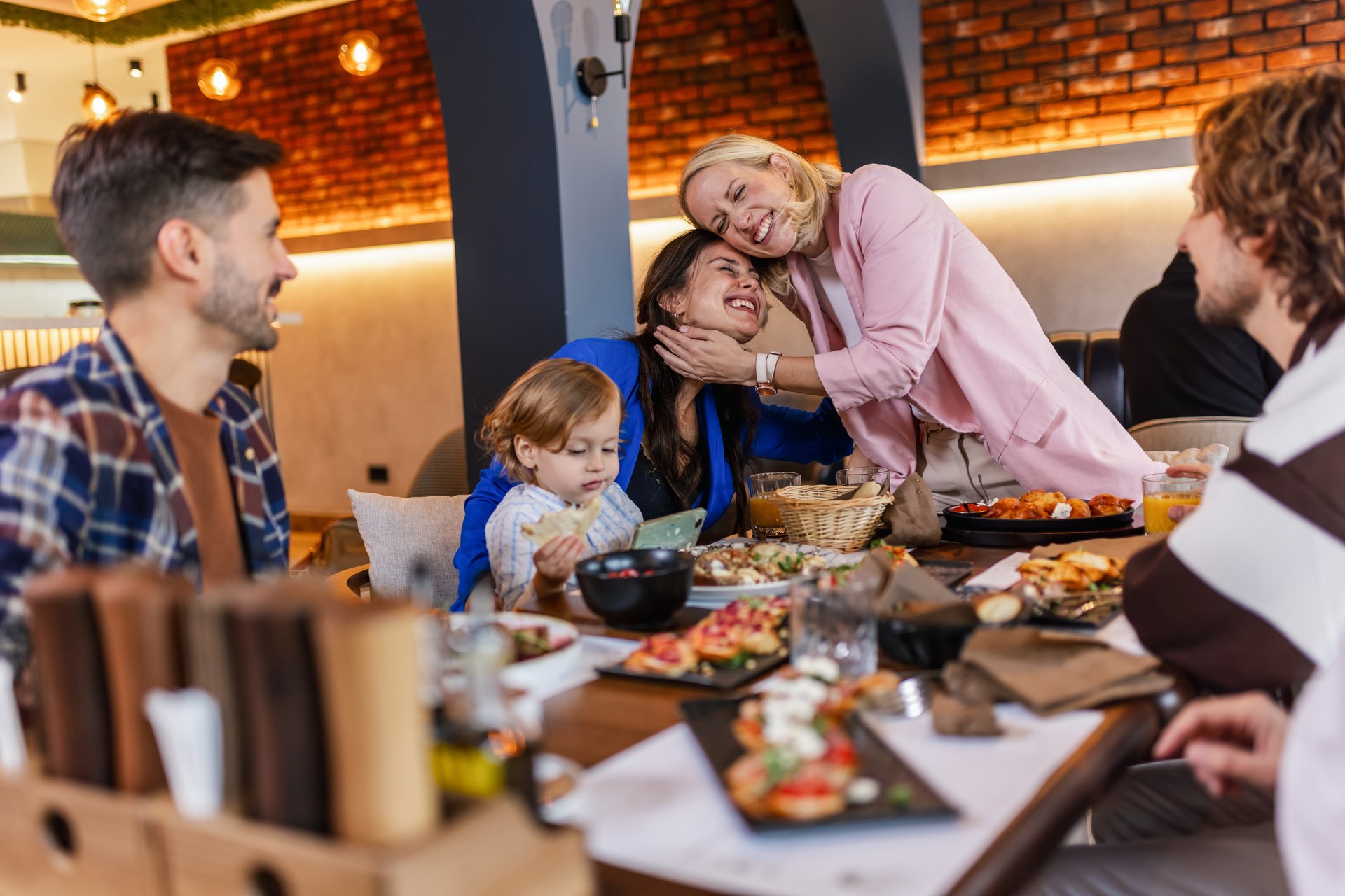 Family and friends gathered in a restaurant to eat delicious food, talk, drink and hang out.