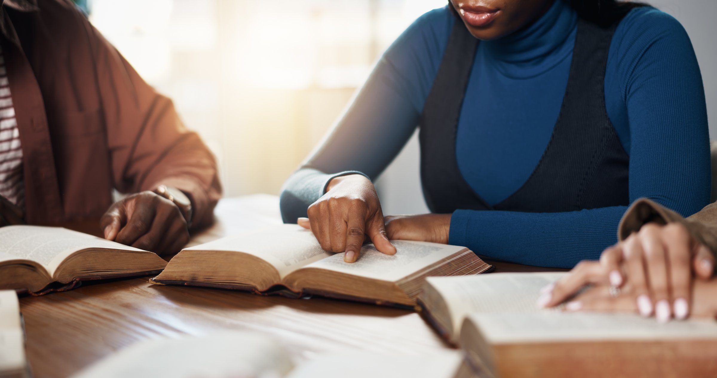 Hands, reading and people for Bible study, worship or group learning gospel for religion. Faith, Christianity and knowledge about God, scripture or theology text for guidance with spiritual growth