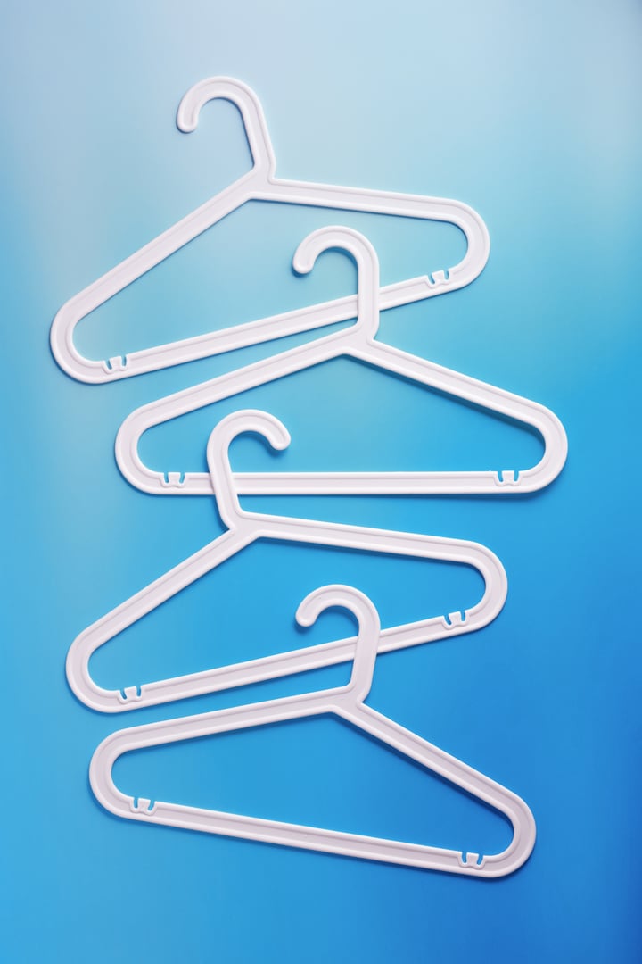 Top view minimal style pattern of white plastic hangers with hooks on blue background. Flat lay with Clothes racks for hanging garments. Minimal trend photo, lifestyle or interior design content