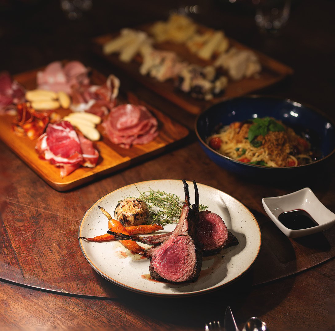Fine Dining Gourmet Platter, A luxurious gourmet dining setup featuring grilled lamb chops, roasted carrots, garlic, charcuterie board