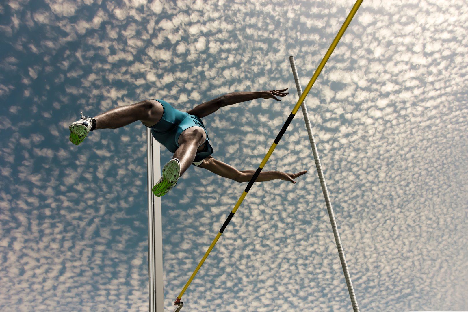 Low Angle View Of Male Athlete High Jumping Against Sky