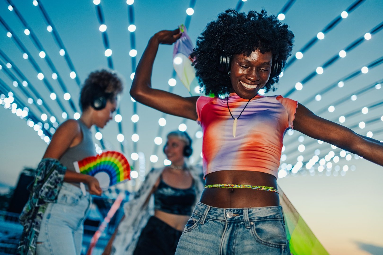 Carefree young woman dancing at silent disco with colorful lights