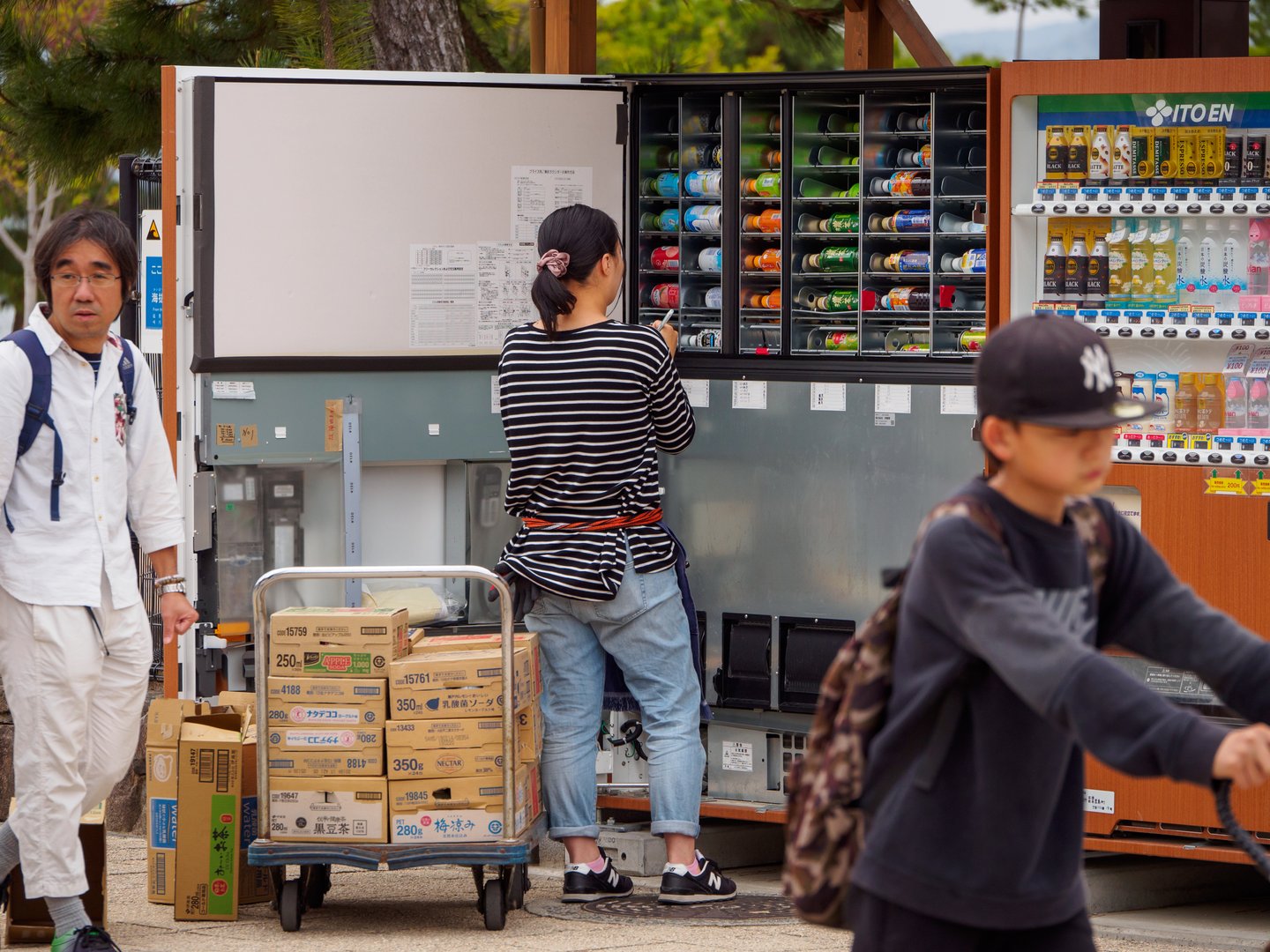 HIROSHIMA, JAPAN - APRIL 4, 2018: A convenience store employee restocks bottled tea and sodas into a vending machine. Miyajima Island. Travel and occupations.