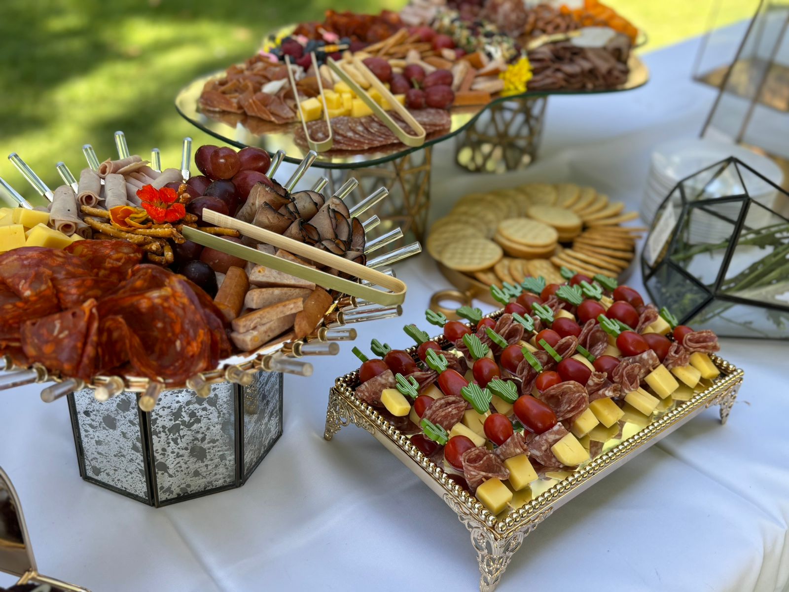 Elegant charcuterie and cheese display with meats, cheeses, fruit, and crackers on decorative platters.