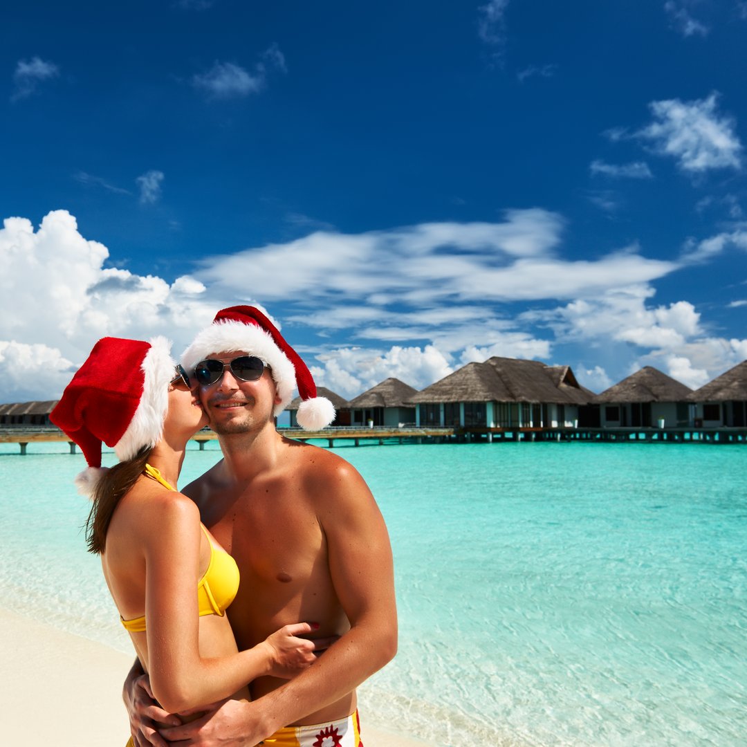 Couple in santa's hat on a tropical beach at Maldives