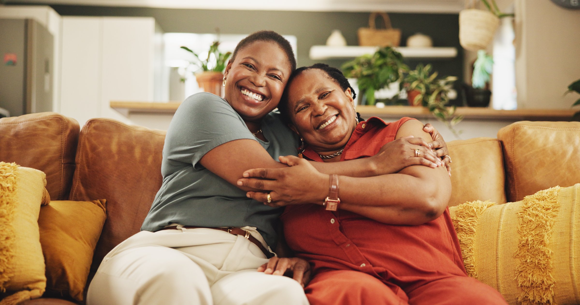 Happy, hug and portrait of black woman with senior mother on sofa in home for womens day celebration together. Smile, bonding and African female person embracing mom for connection in living room.