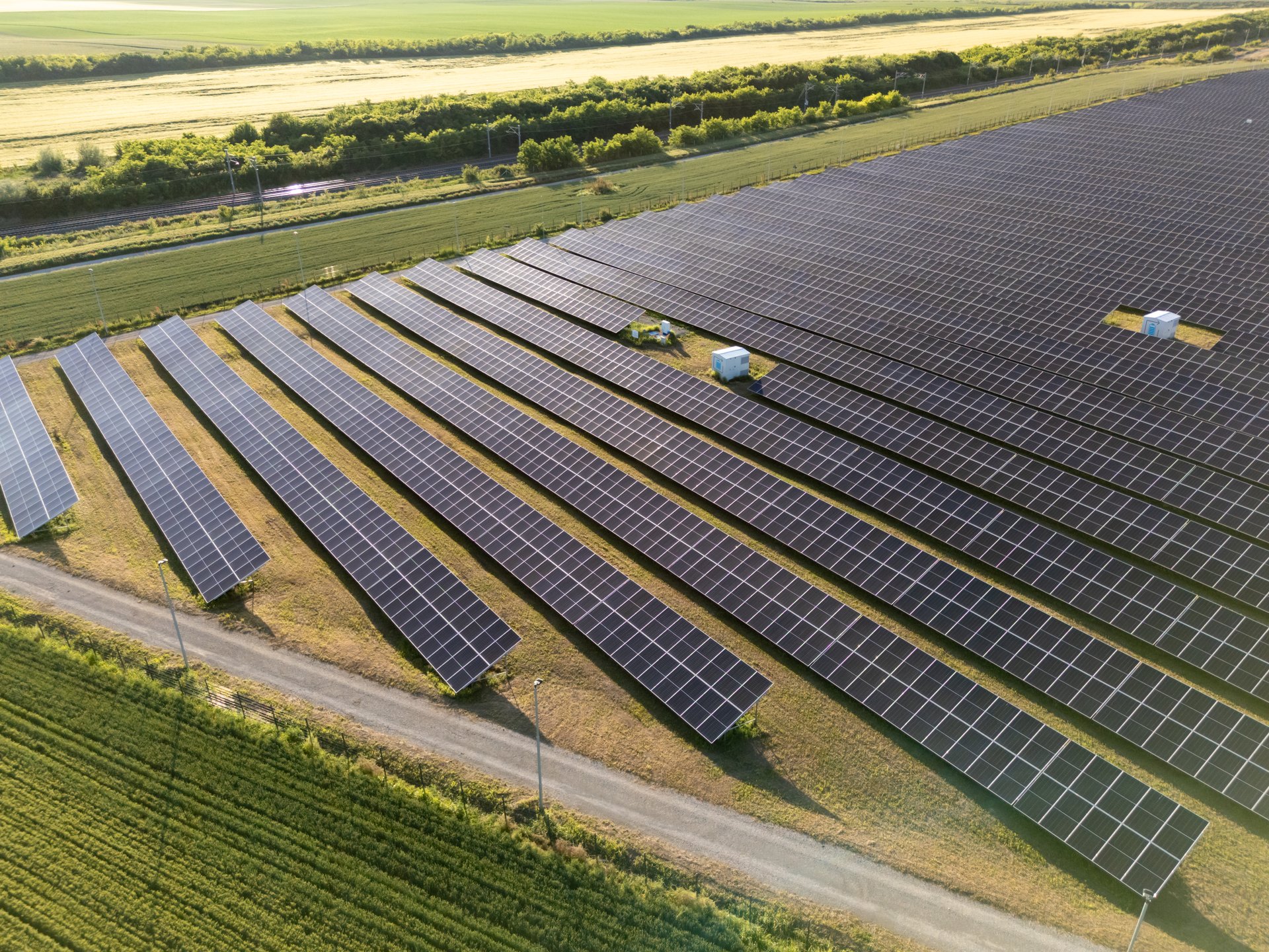 Drone point of view of agricultural field with photovoltaic power station. There are a lot of solar panels at sunset.