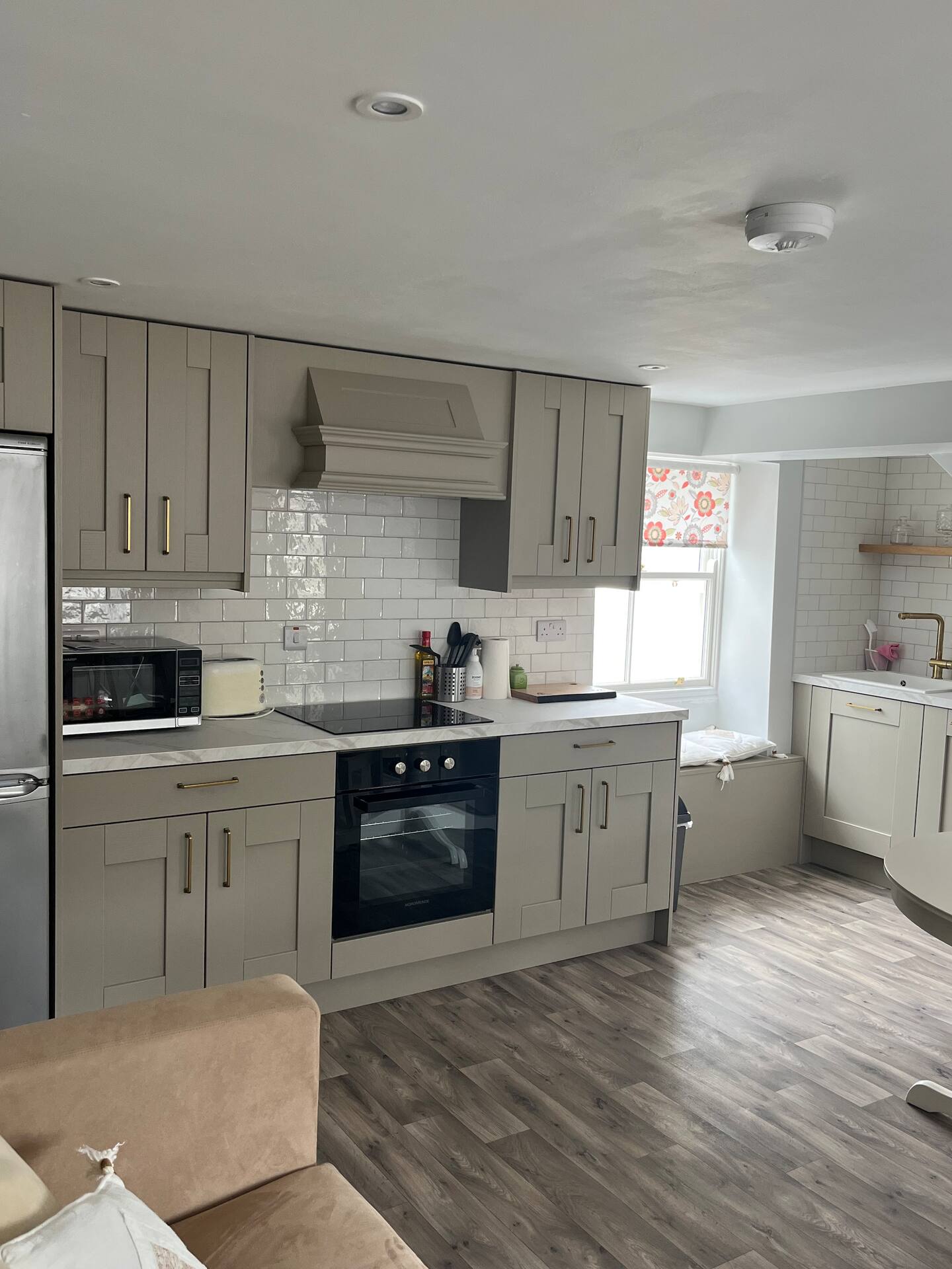 Modern kitchen with gray cabinets, stainless steel appliances, subway tile backsplash, and wood flooring.