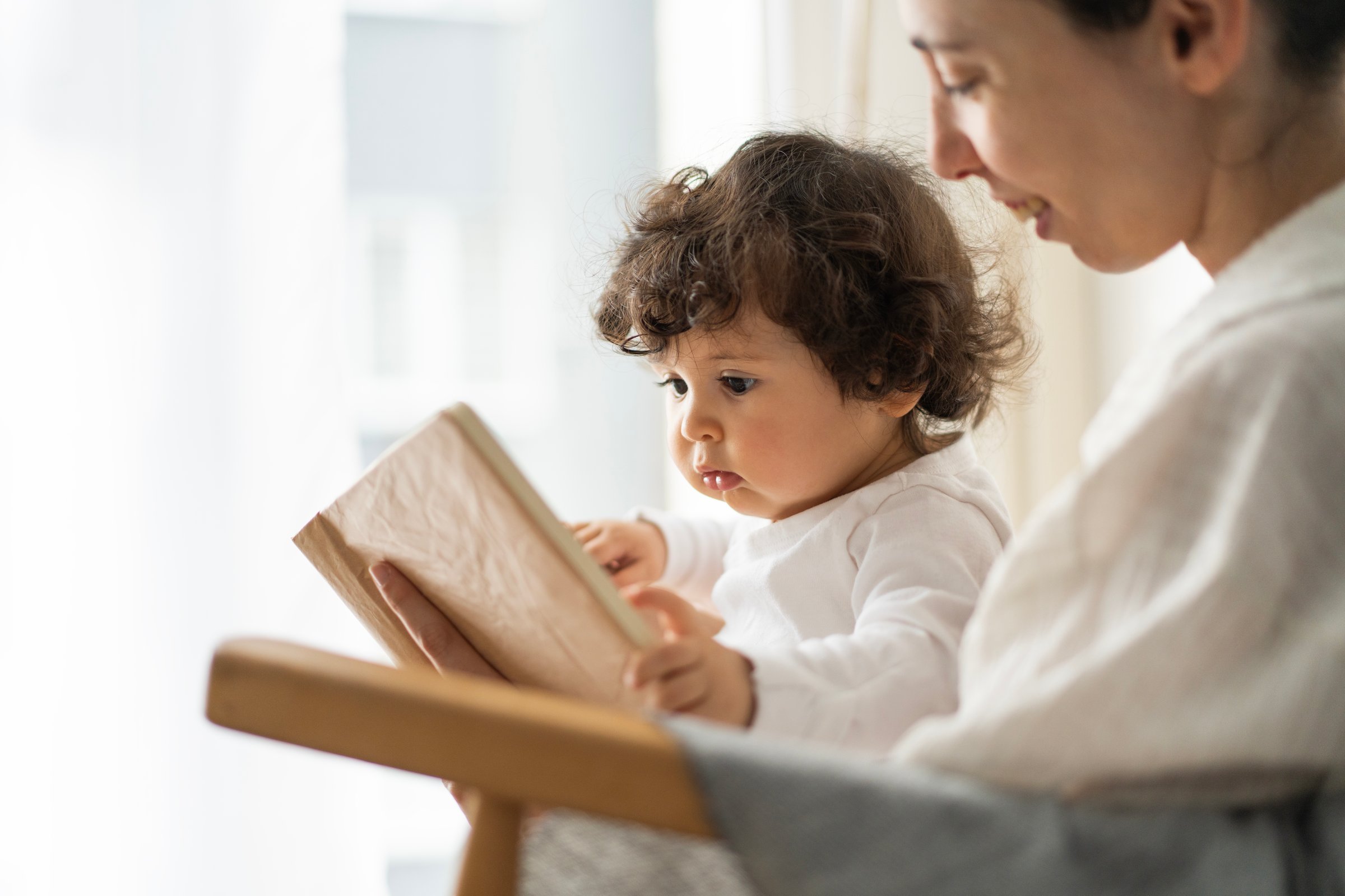 Mother Reading Book with Adorable Toddler Daughter