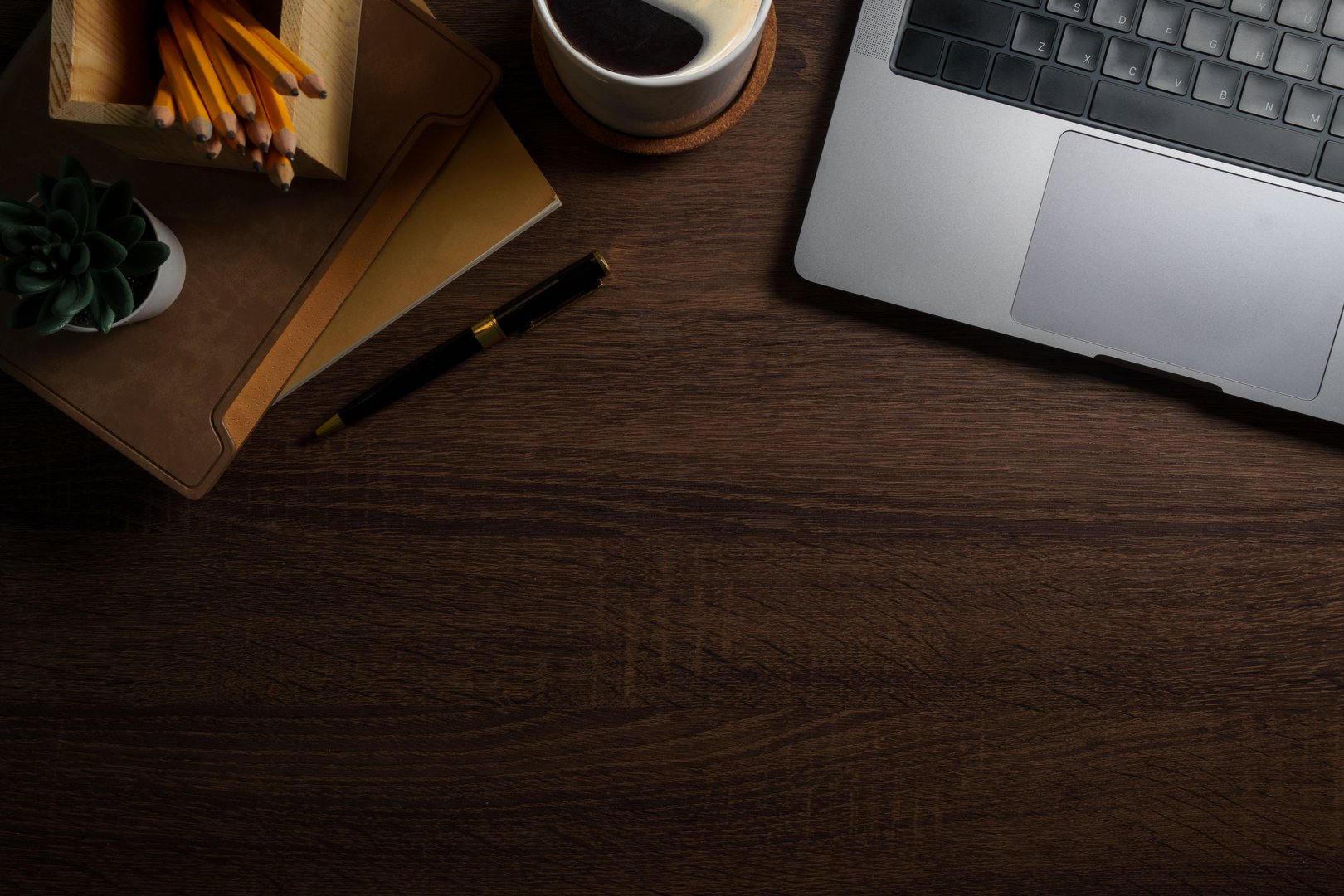 Modern workplace with laptop computer, coffee cup and pencils on wooden background. Top view.