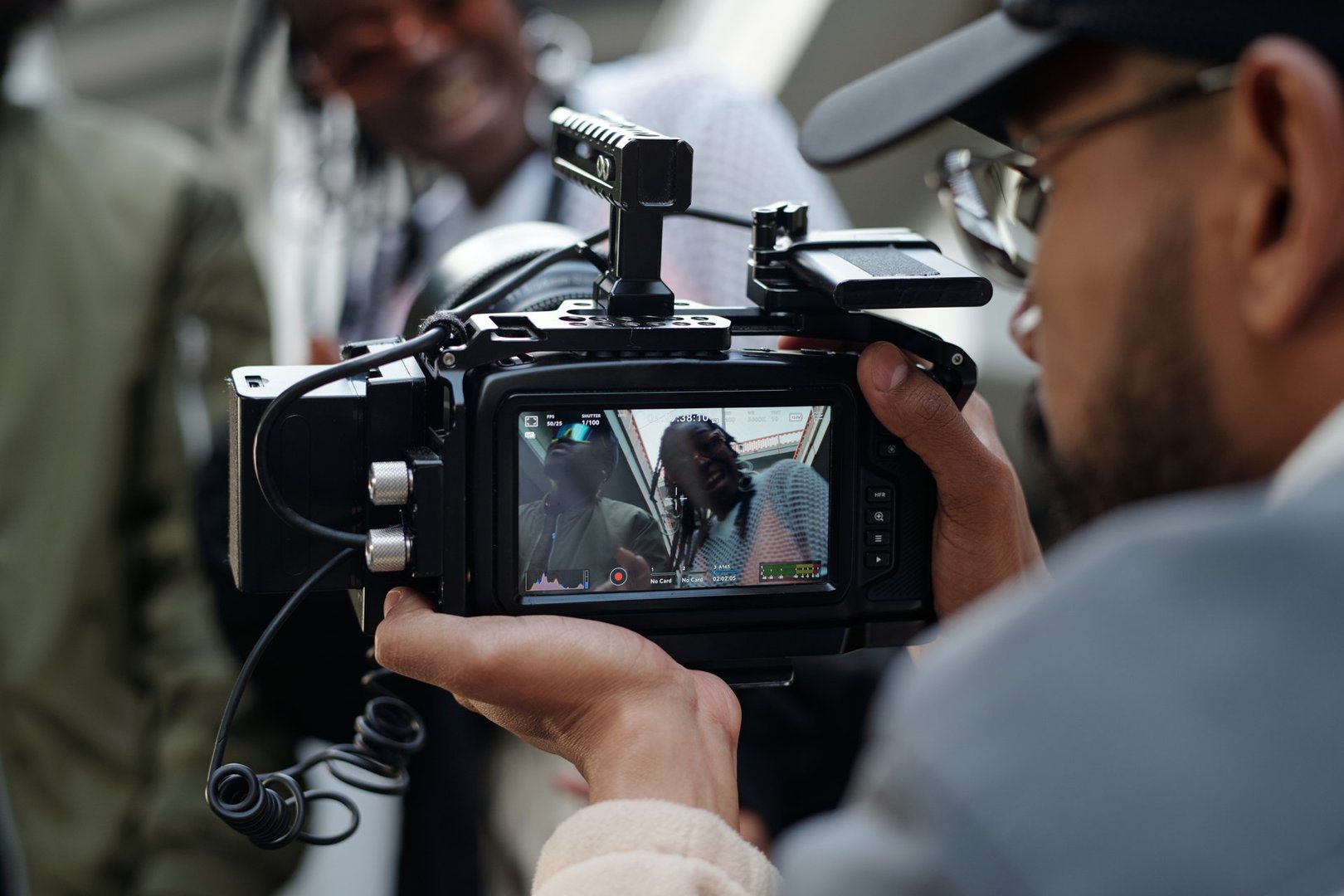 Close-up shot of a camera operator filming a person engaging in conversation, seen through the viewfinder, capturing precise details and interactions without using natural light