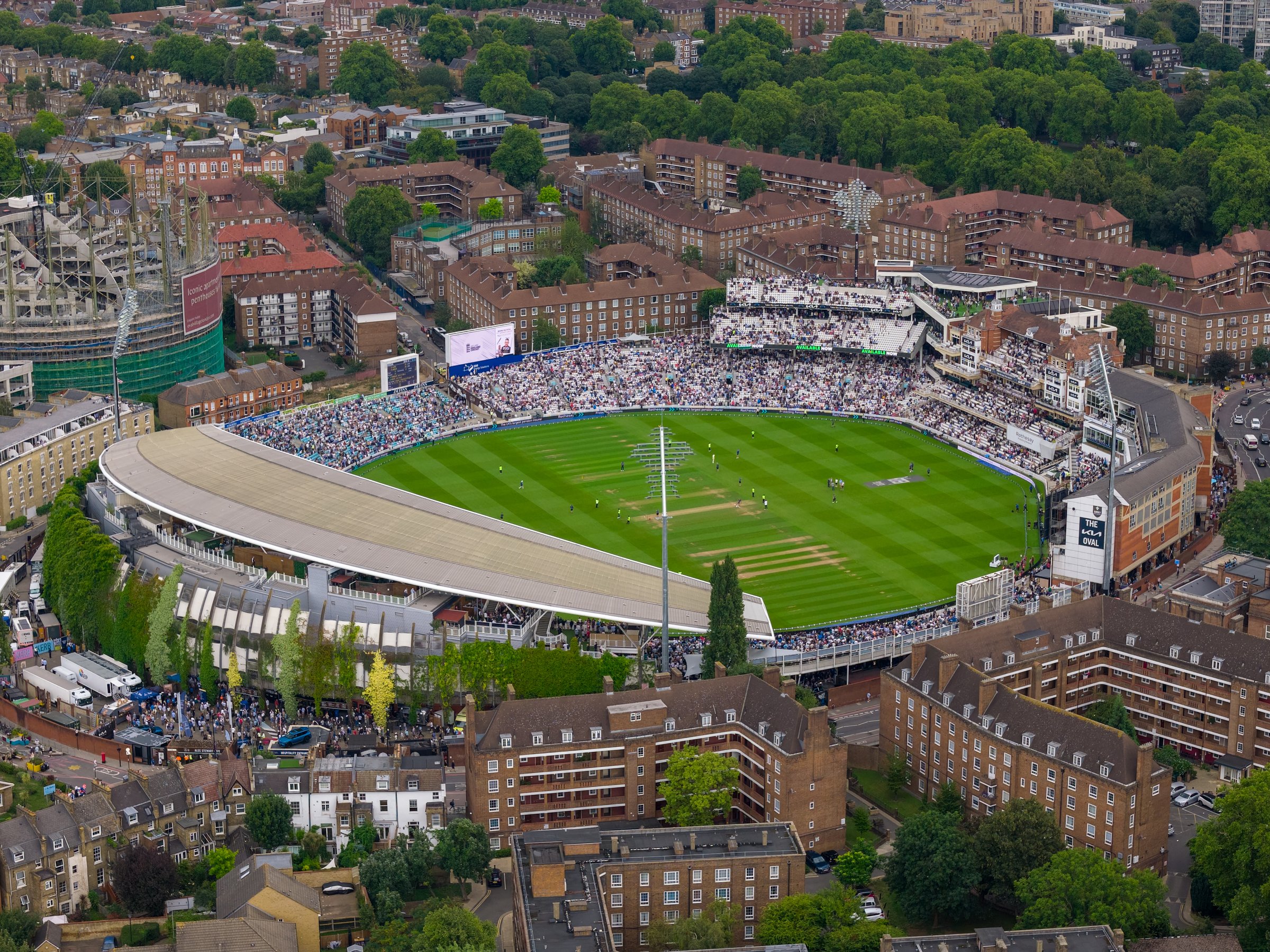 Aerial view of The Oval cricket stadium in London during a match day, surrounded by residential buildings and greenery.