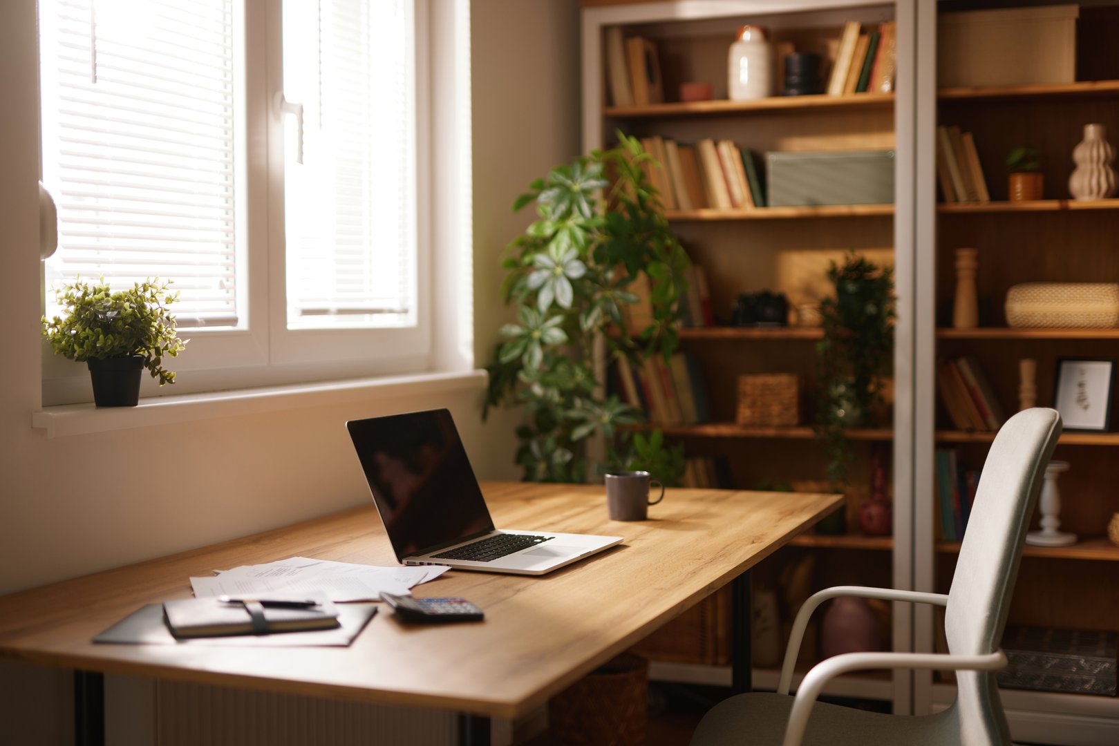 Modern home office with laptop, calculator, and documents on a wooden desk, promoting a productive work environment