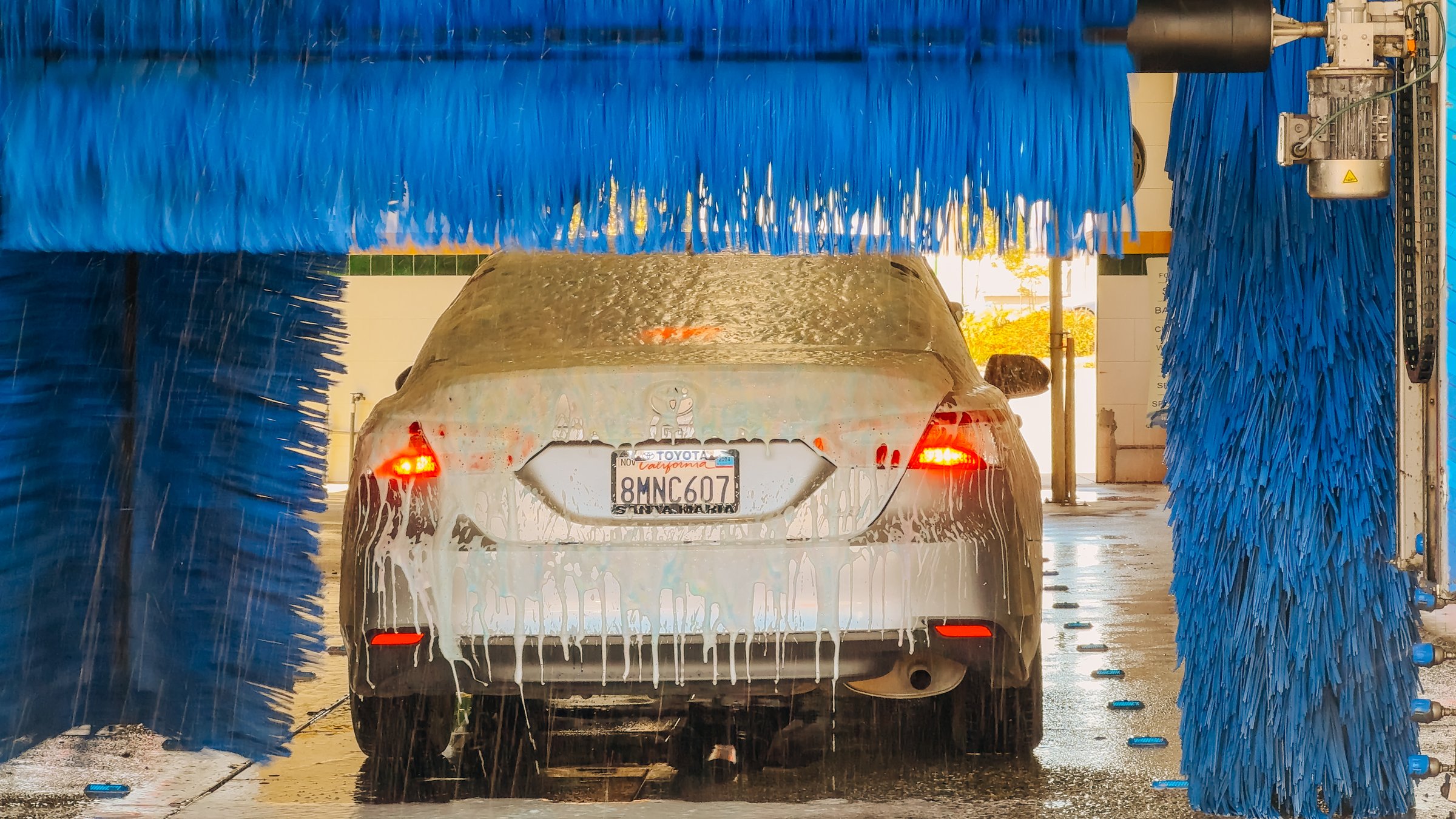 Blue brushes clean a vehicle as it moves through the car wash station