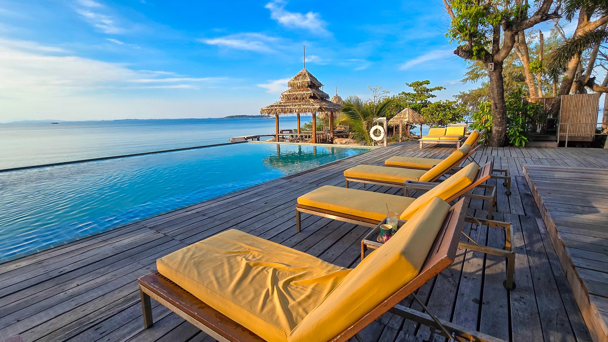 Lounging by the infinity pool on Koh Munnork Island offers breathtaking views of the turquoise ocean under a clear blue sky. This tranquil paradise is perfect for relaxation and escape in Thailand.