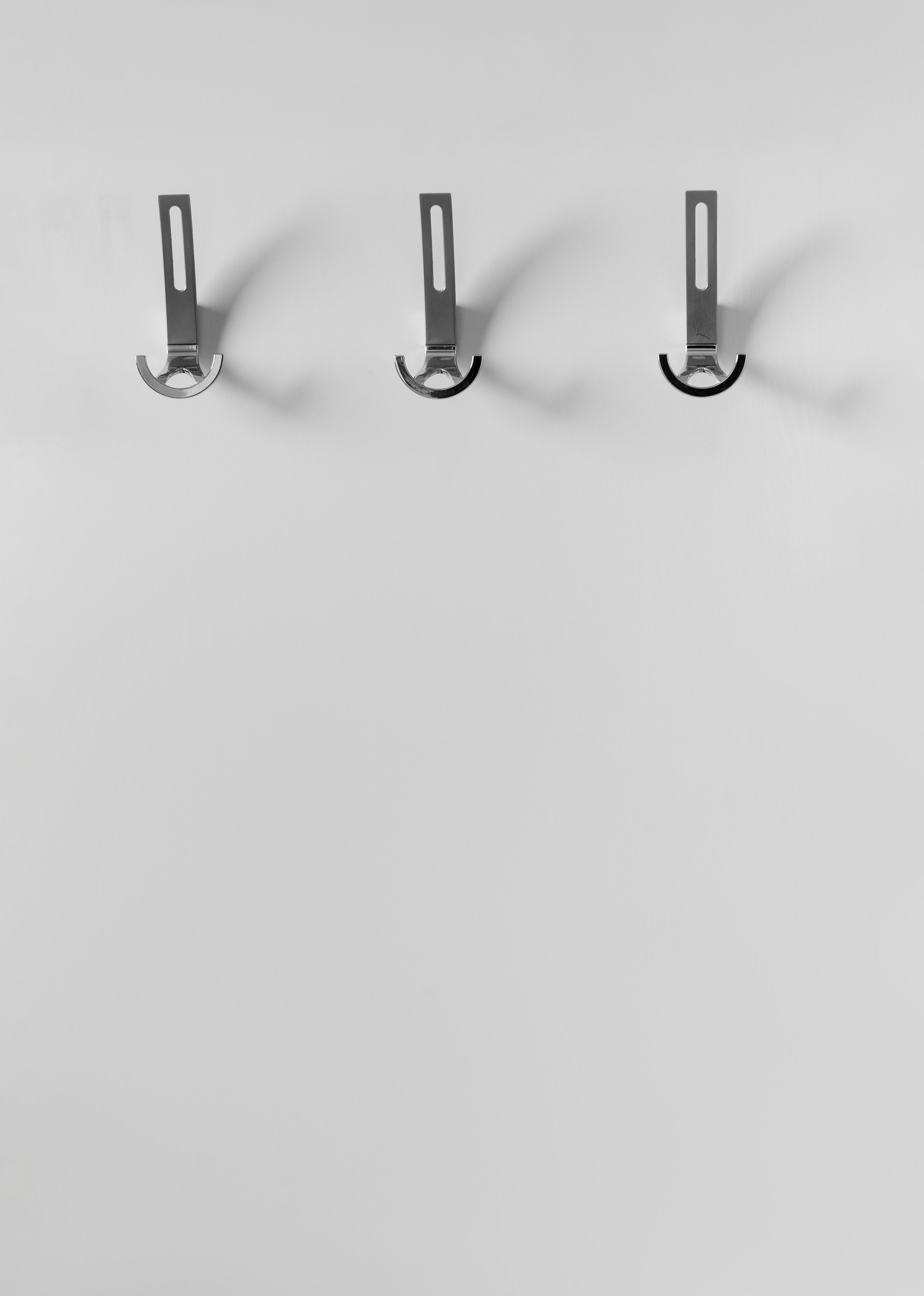 Hanger for outerwear with metal hooks on a white wall in a modern interior of the hallway of an apartment, house. Elements of interior, design of premises.