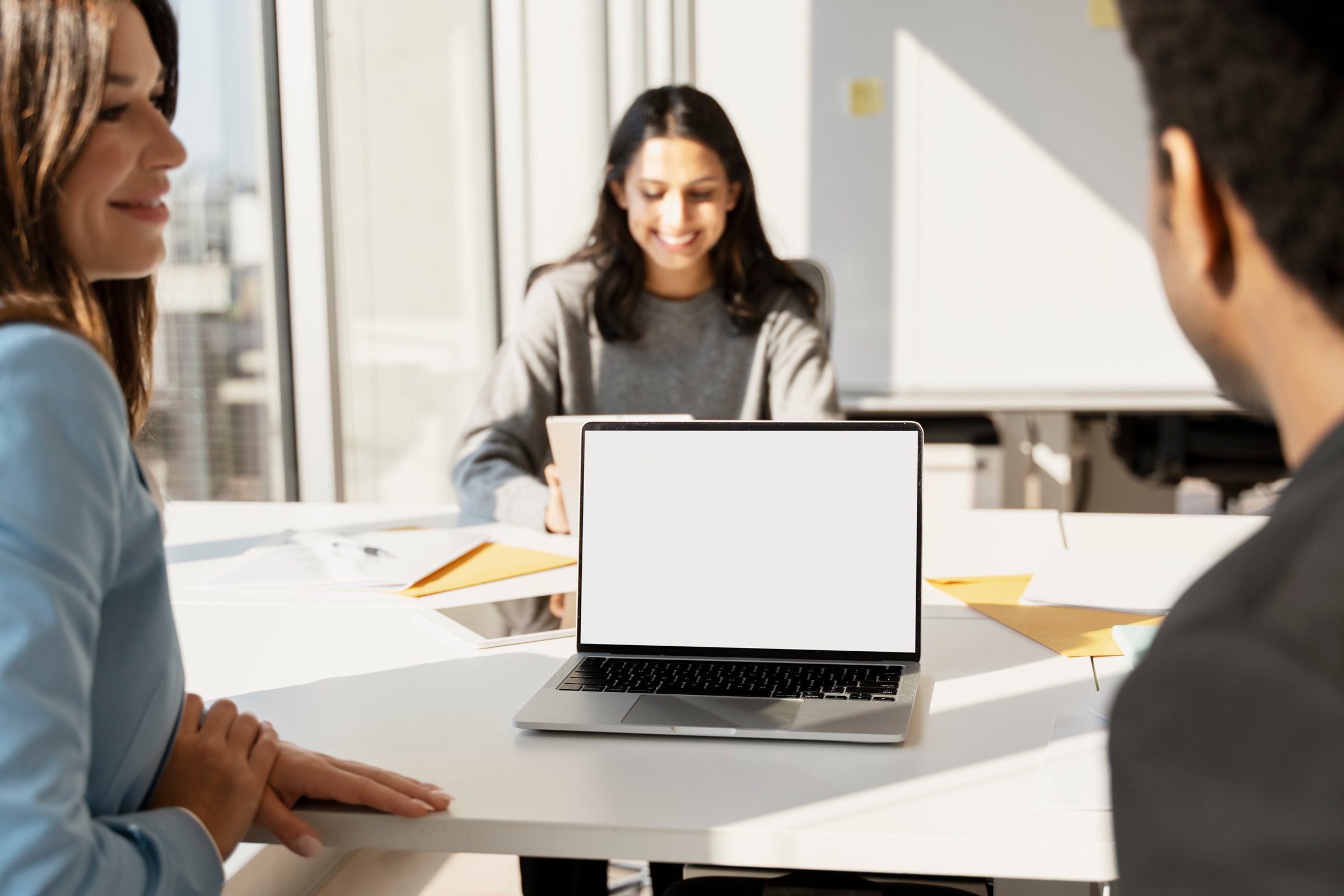 Coworkers using laptop with blank screen during meeting in modern office, mockup, copy space
