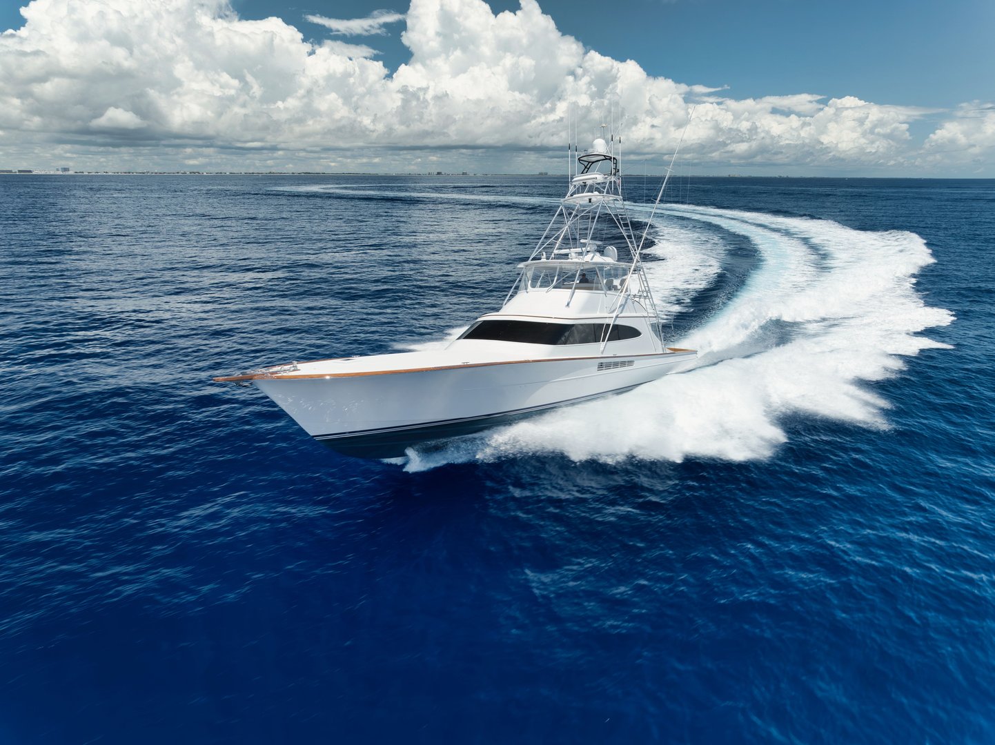 A luxury yacht speeding through the ocean under a partly cloudy sky