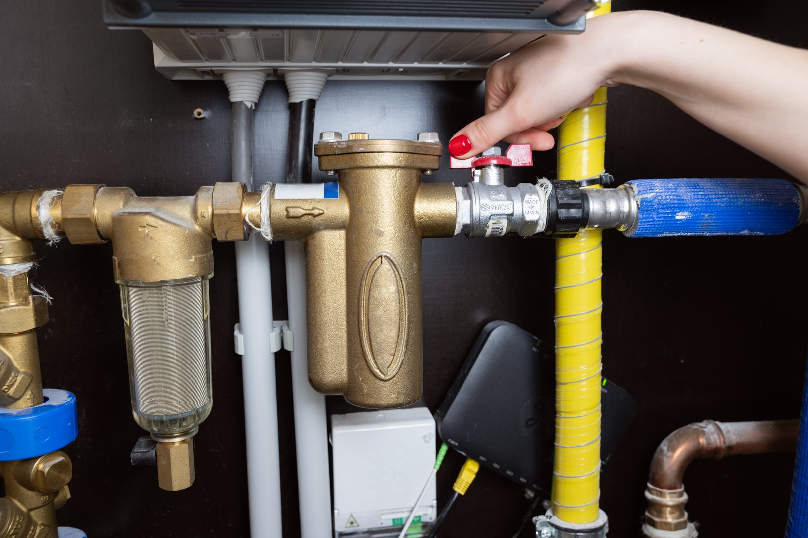 A closeup image shows a hand skillfully operating a plumbing valve, highlighting modern heating system components