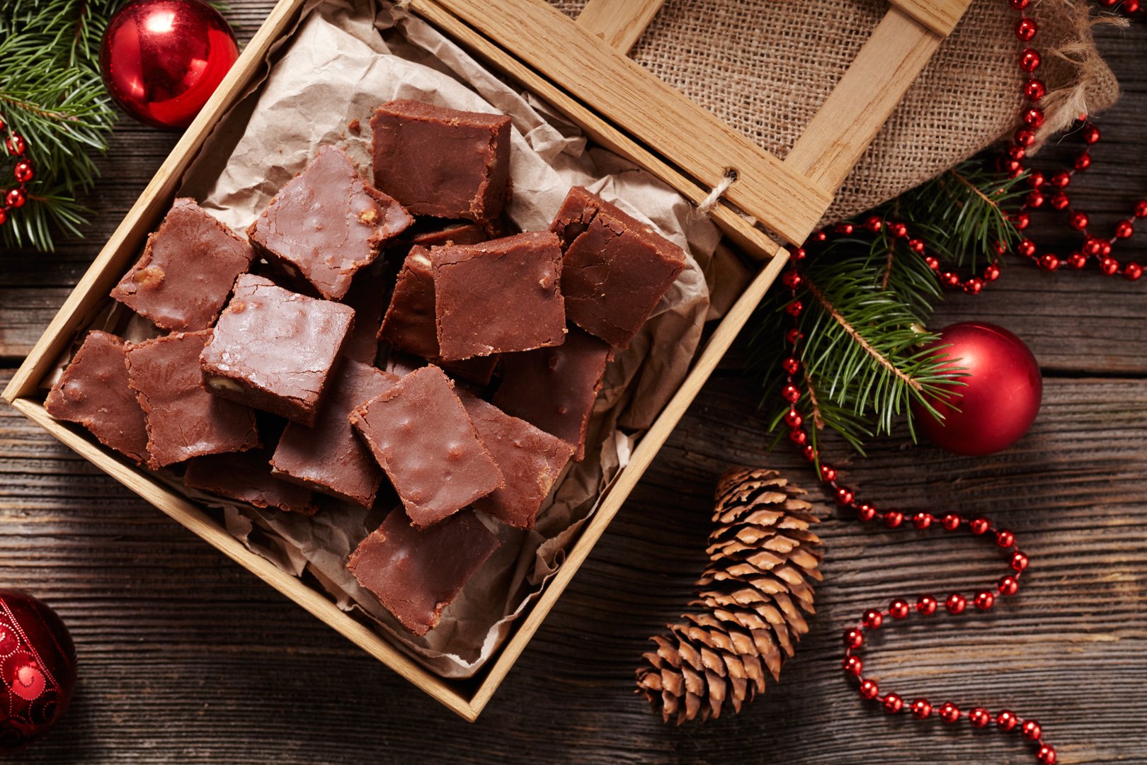 Christmas fudge traditional homemade chocolate sweet dessert food in wooden box on vintage table background. Top view. Delicious unhealthy treat.