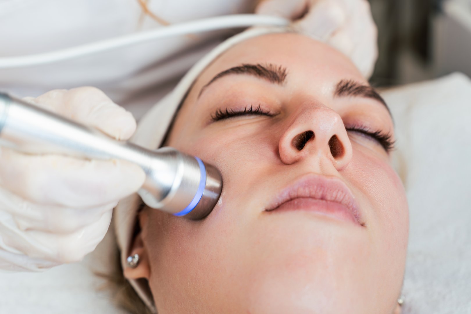 Young woman receiving modern facial low-voltage electrical treatment to stimulate elastin and collagen production for facial muscles improvement. Most popular face lifting treatment. Cosmetician work.