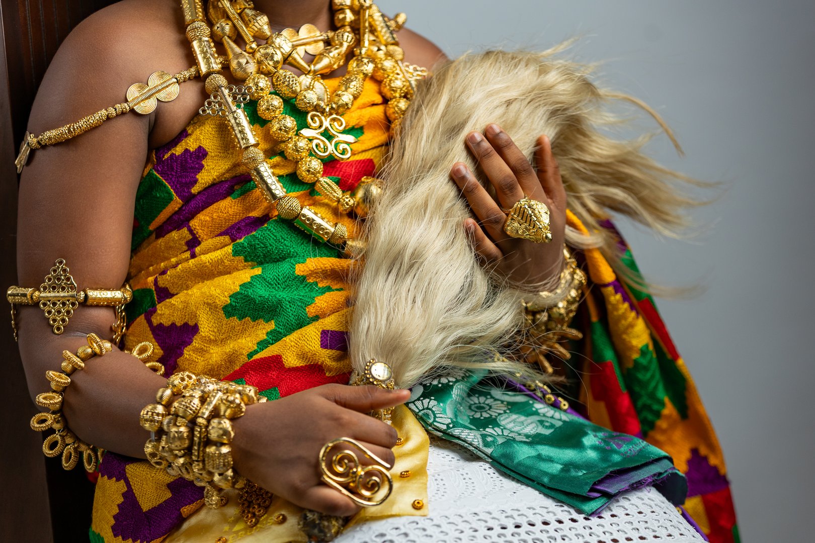 Rich Ghanaian royalty regalia. Traditional African culture and heritage, whisk, gold ring jewellery, necklace and bracelet ornaments worn on Kente cloth.