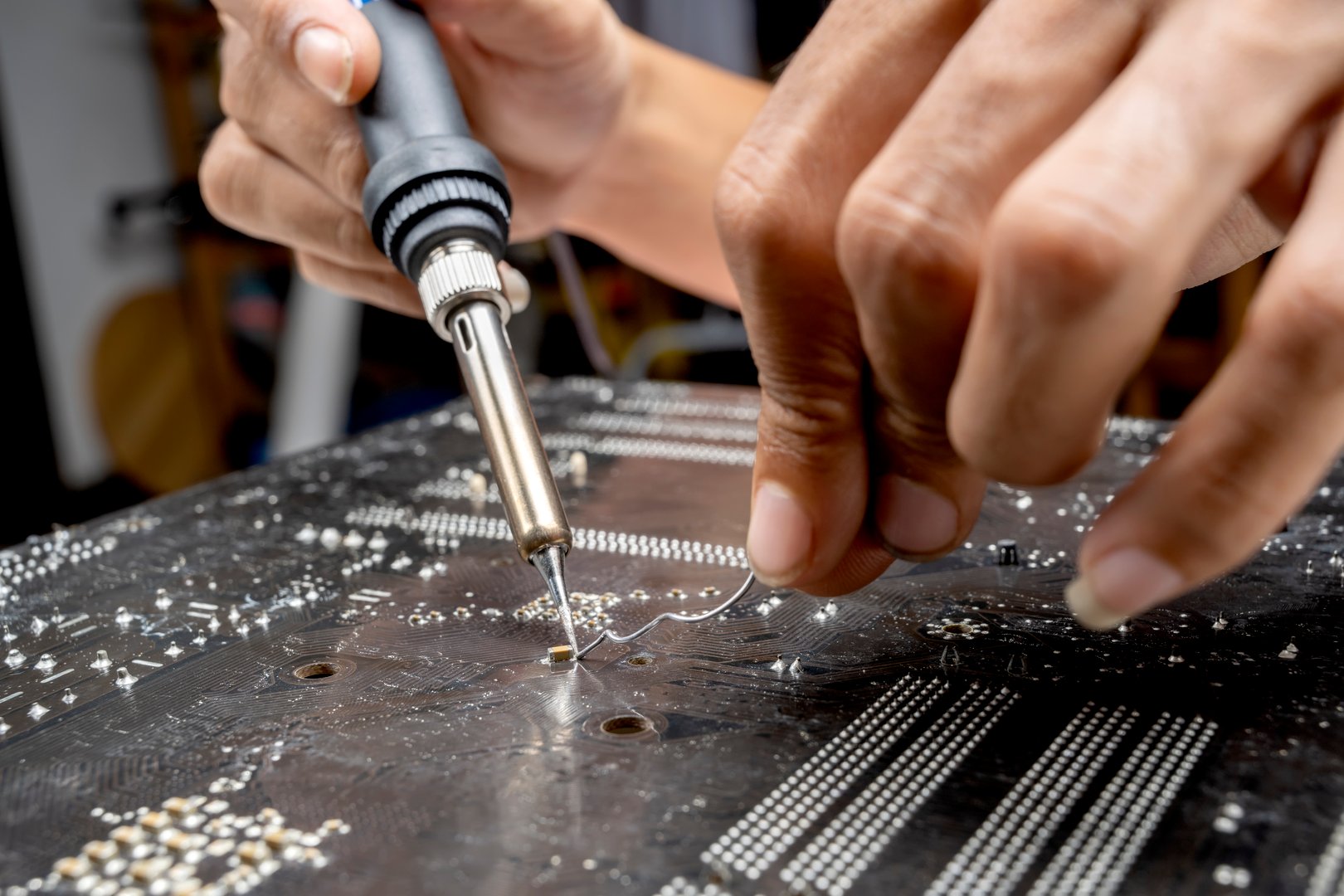 Man technician soldering a circuit board. Service, maintenance or repairing concept