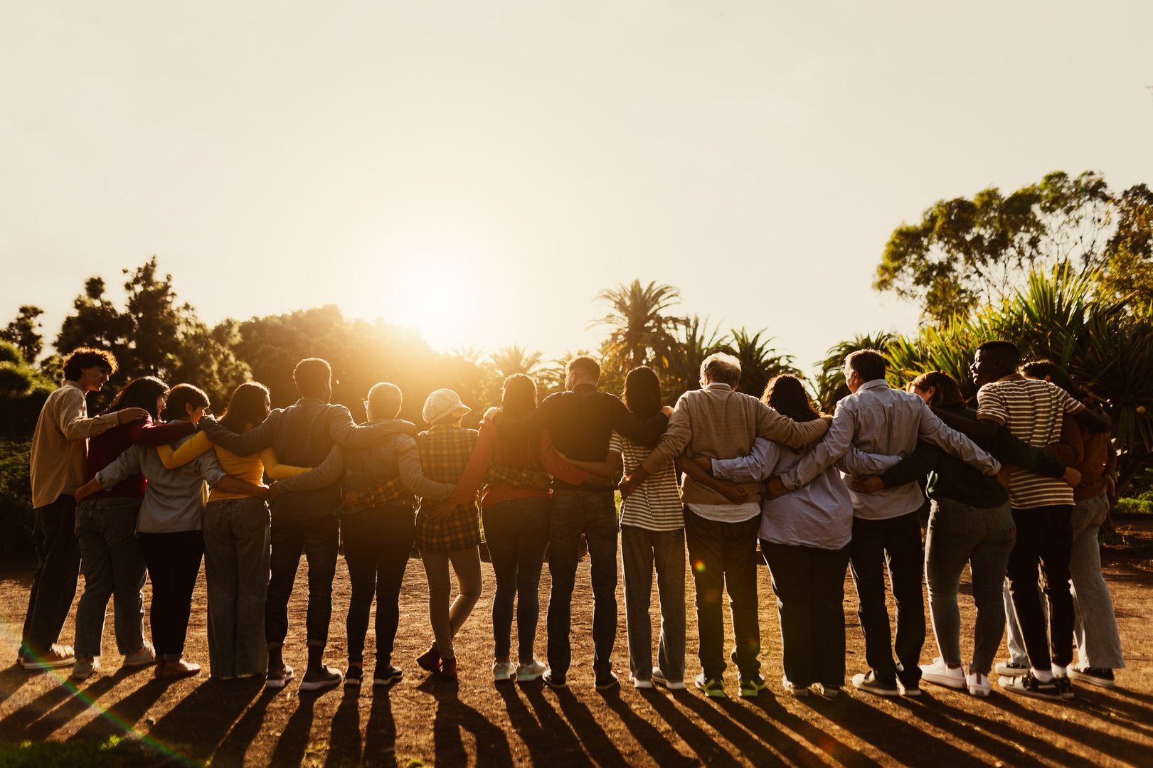 Back view of happy multigenerational people having fun in a public park during sunset time - Community and support concept