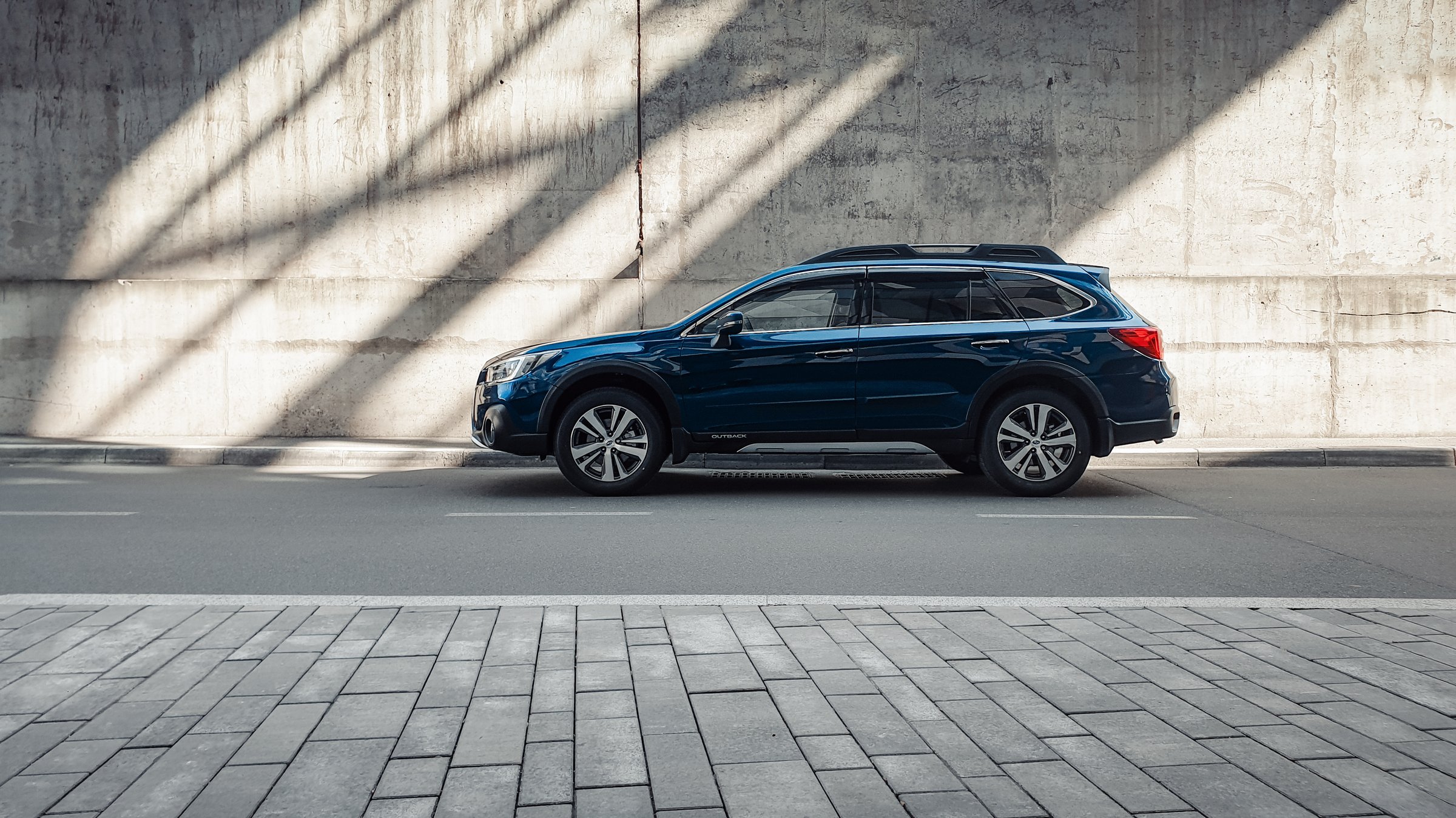 Side profile view of family wagon crossover on a sunny day, shadows and light beams on grey wall in the back. Kyiv, Ukraine - March 24 2020.