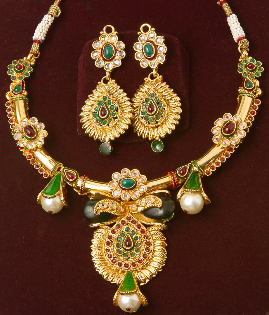This is an image of a necklace and a pair of earrings set against a velvet background