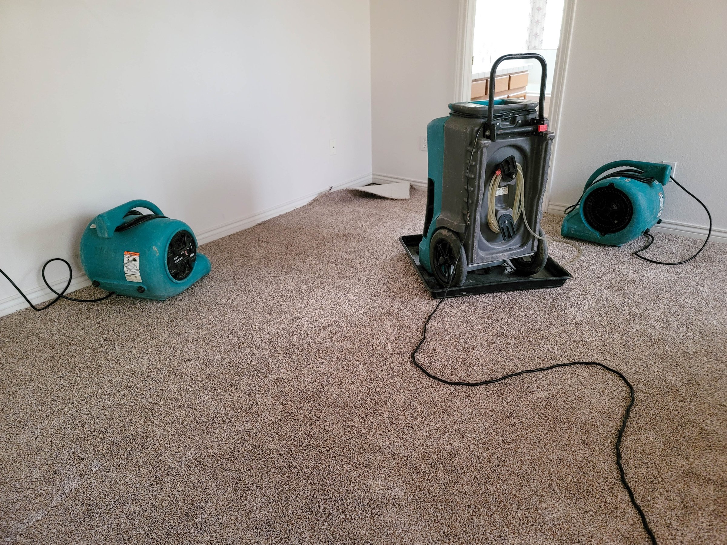 Two air movers and a dehumidifier drying a home