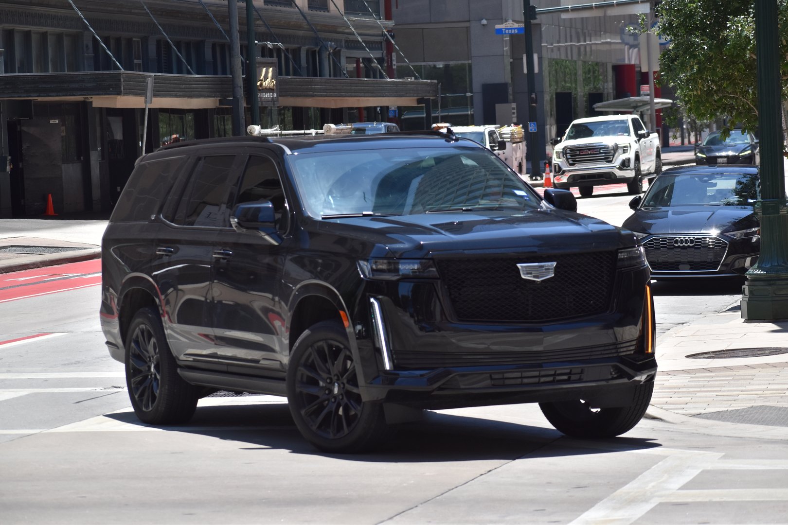 Houston, TX - 5/15/2024 A portrait of a black Cadillac Escalade Sport SUV cruising in a downtown district