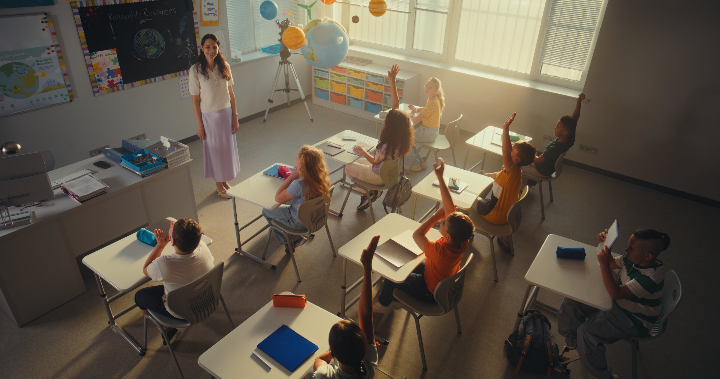 Female Teacher Teaching Kids During Environmental Science Lesson in Modern Classroom. Smart Children Raising Hands, Primary School Girl Showcasing Knowledge of Ecology in Front of Class. High Angle.